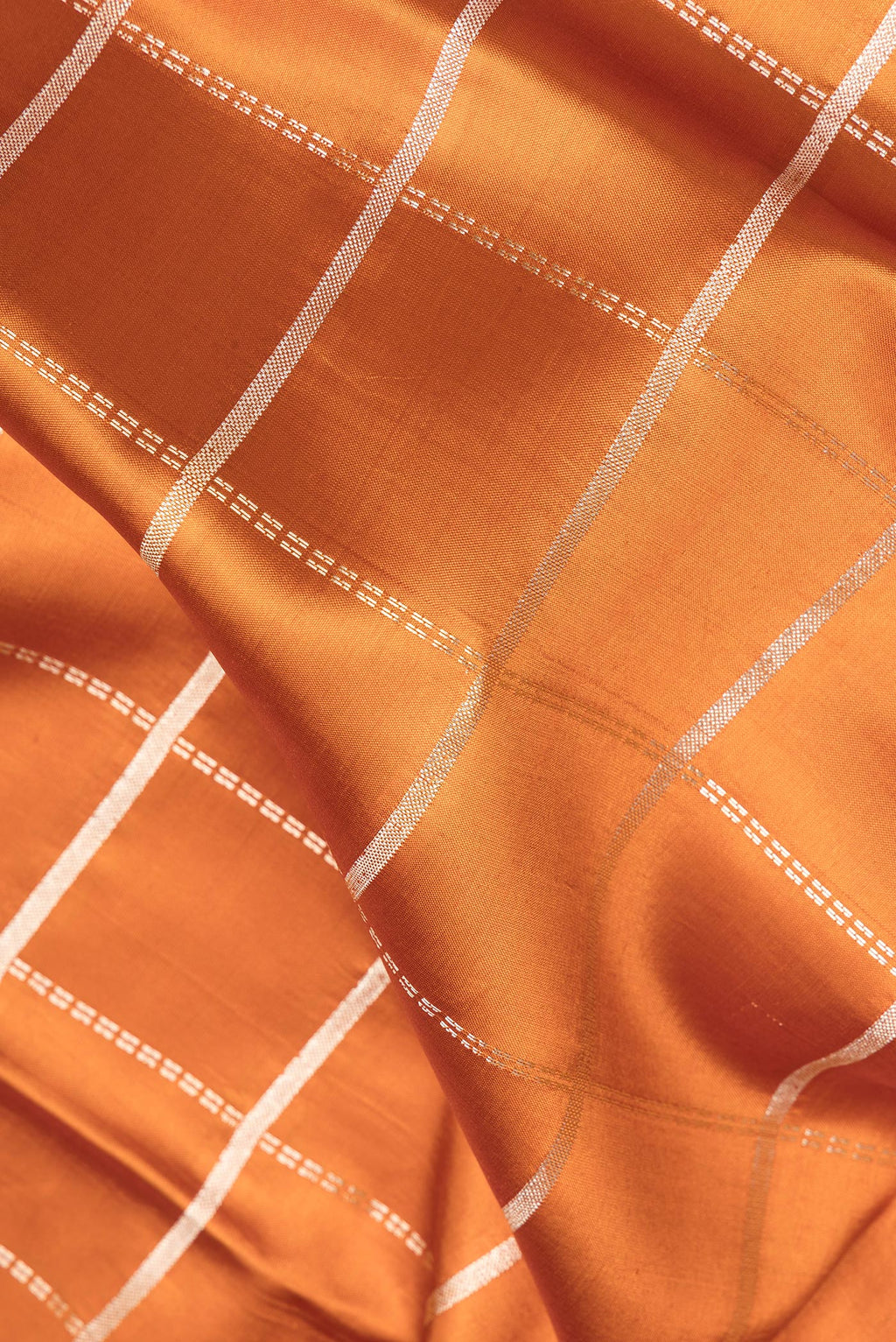 Close up of Pure Silk Rust Dual Tone Tussar Saree with Checked design on the body and Fancy Border.  displaying folds