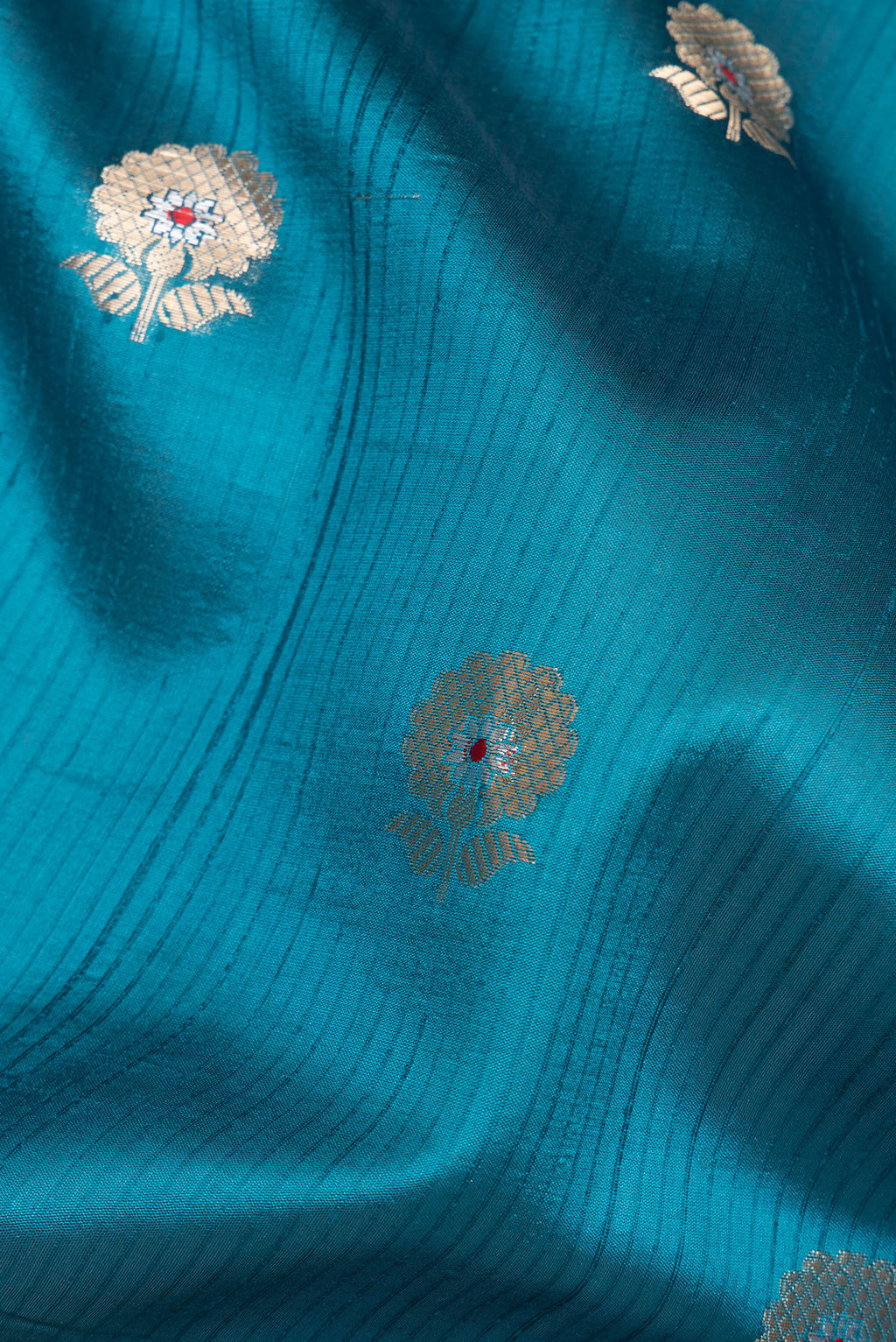 Close up of Pure Silk Peacock Blue Dual Tone Tussar Saree with Zari Butta on the body and Fancy Border.  displaying folds