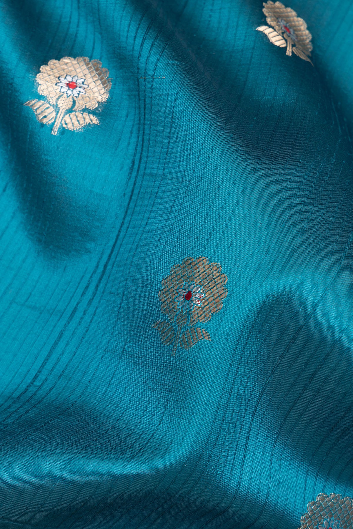 Close up of Pure Silk Peacock Blue Dual Tone Tussar Saree with Zari Butta on the body and Fancy Border.  displaying folds