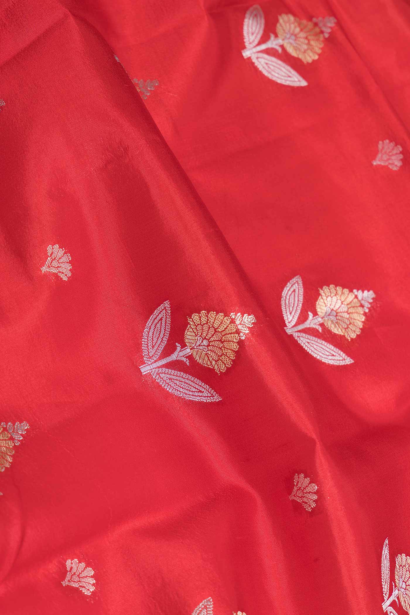 Close up of Red Banarasi Raw Silk Saree with Zari Butta on the body and Zari Border displaying folds