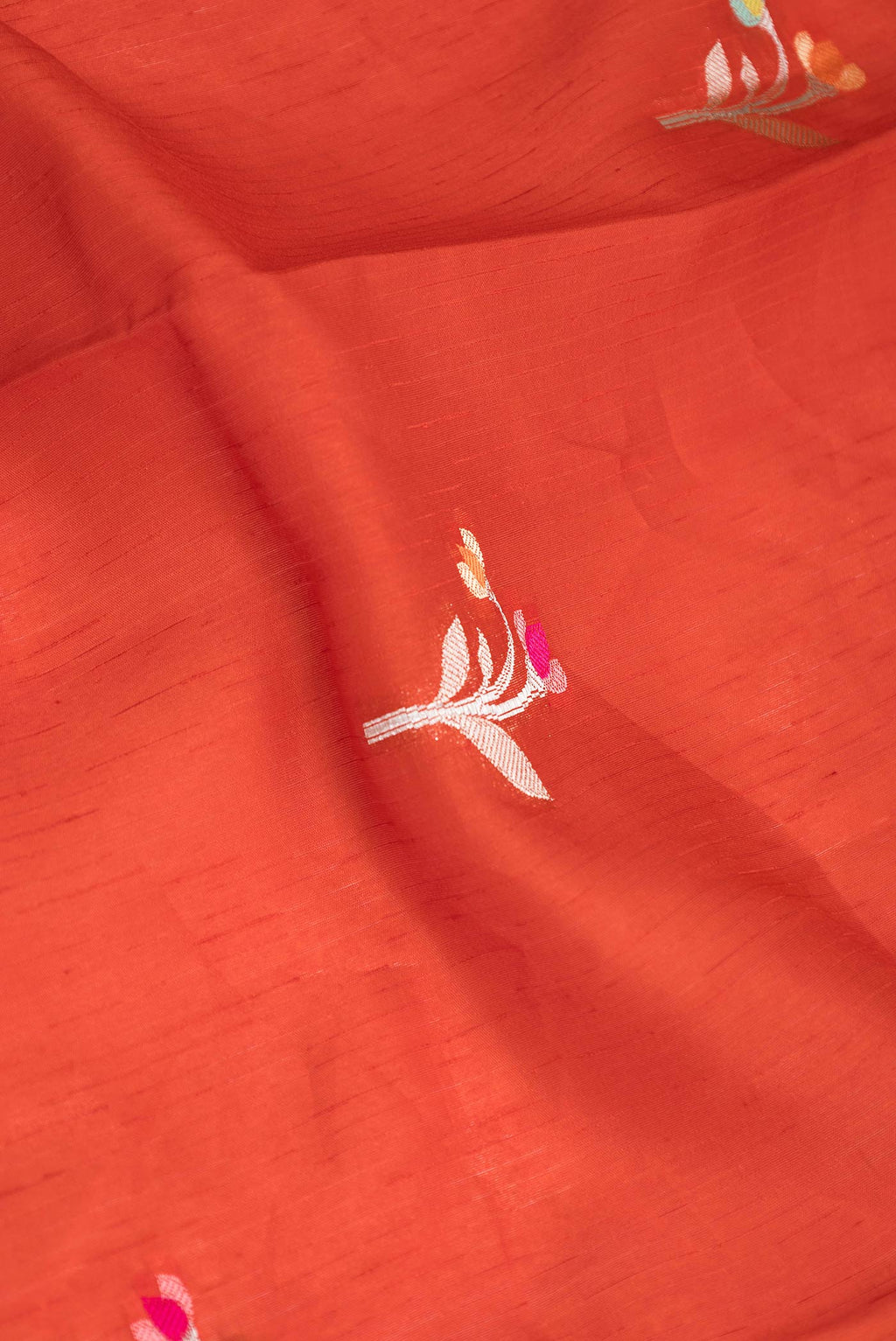 Close up of Red Banarasi Raw Silk Saree with Zari And Thread Butta on the body and Zari Border displaying folds