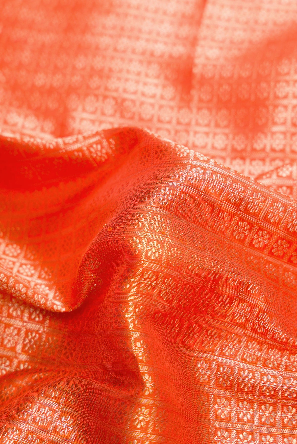 Close up of Brick Orange Dual Tone Kanchipuram Silk Saree with Zari Brocade on the body and Zari Border.  displaying folds
