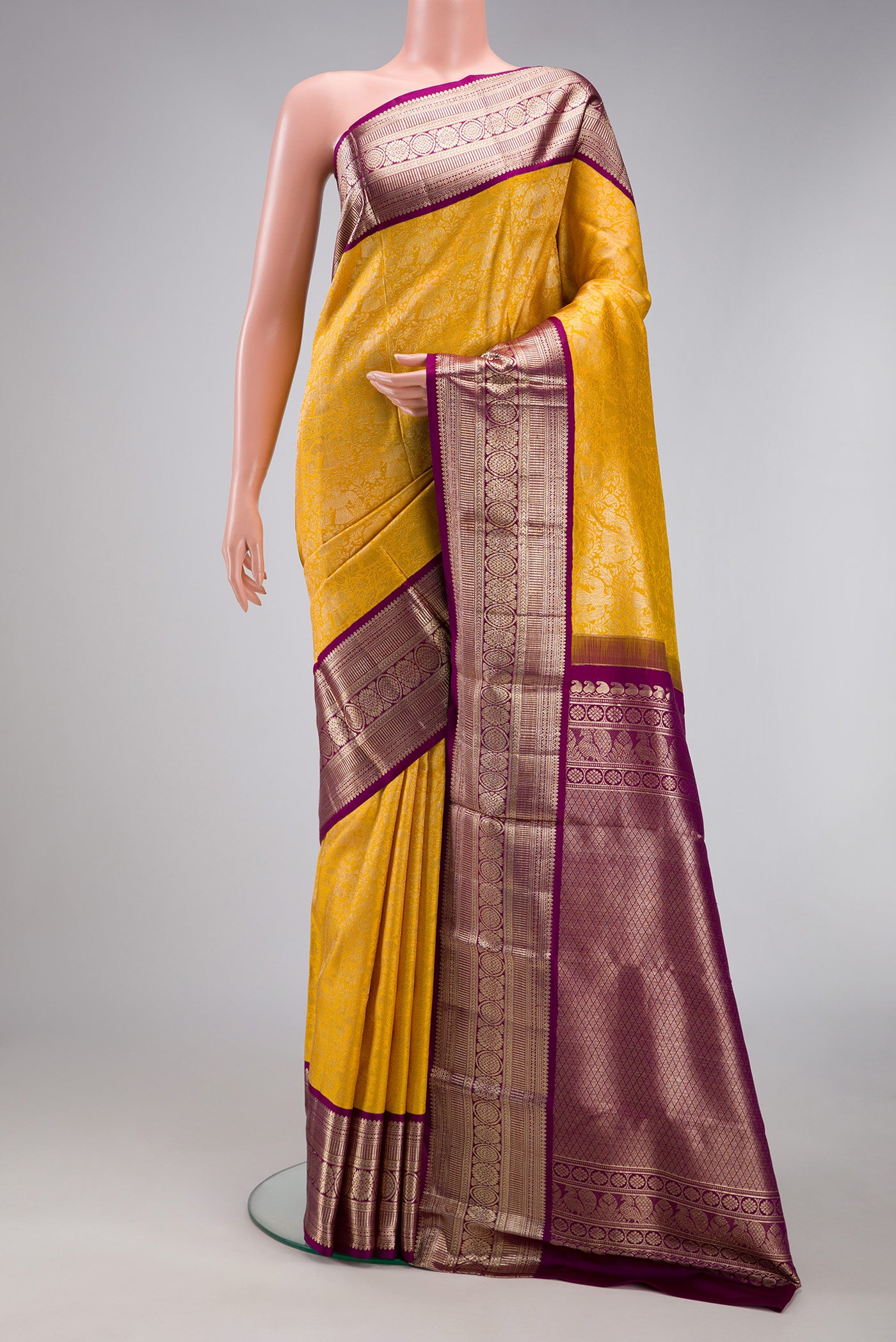 Yellow Kanchipuram Silk Saree with Zari Brocade on the body and Zari Border.  displayed on a mannequin