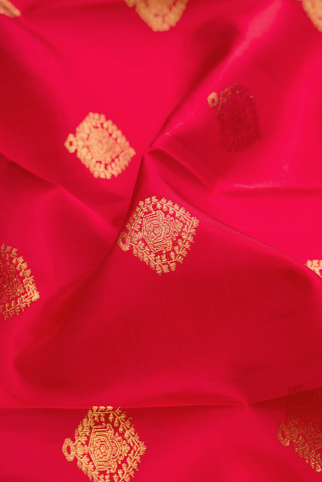 Close up of Maroon Dual Tone Kanjivaram Silk Saree with Zari Butta on the body and Fancy Border.  displaying folds