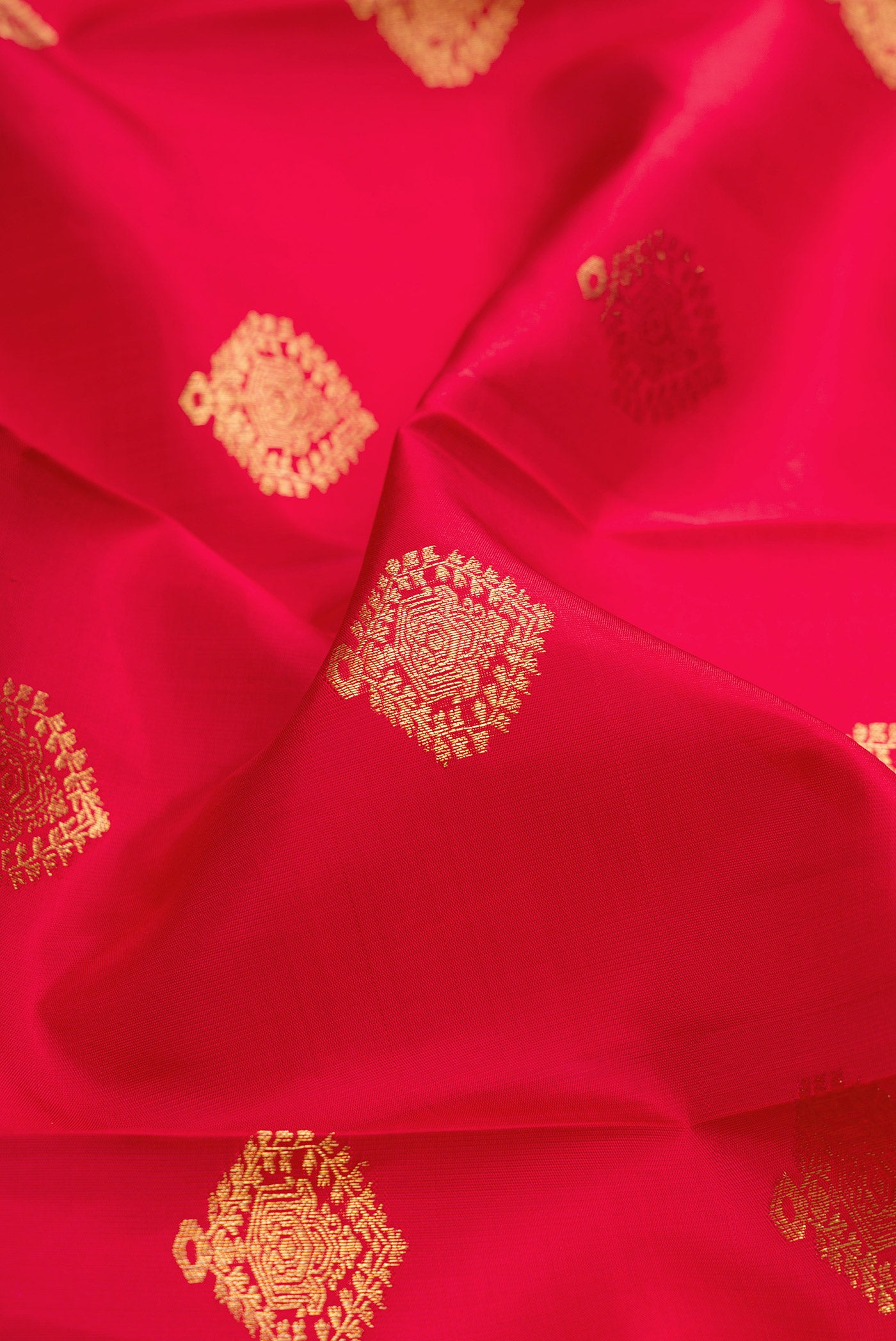 Close up of Maroon Dual Tone Kanjivaram Silk Saree with Zari Butta on the body and Fancy Border.  displaying folds