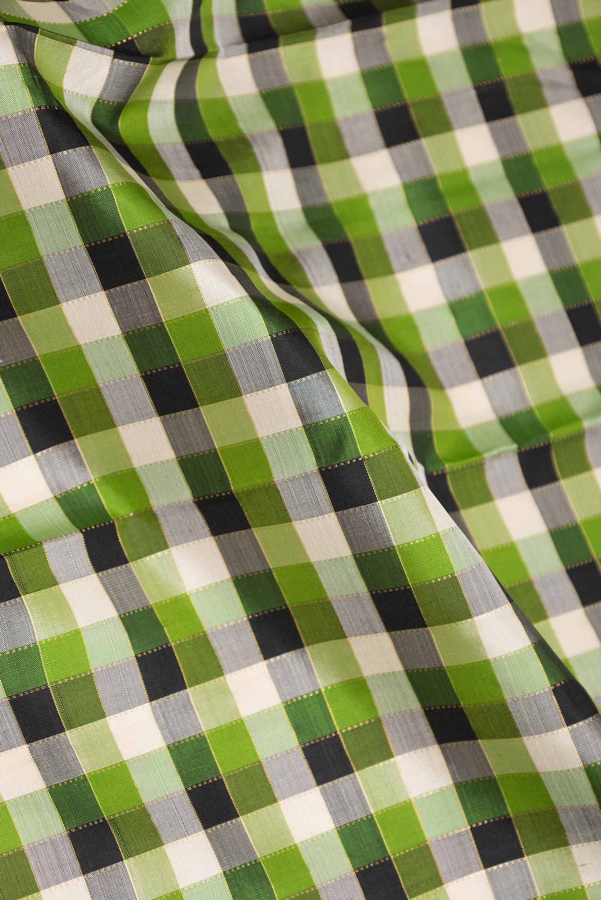 Close up of Green,Black and Beige Color Kanchipuram Silk Saree with Checked design on the body and Zari Border displaying folds