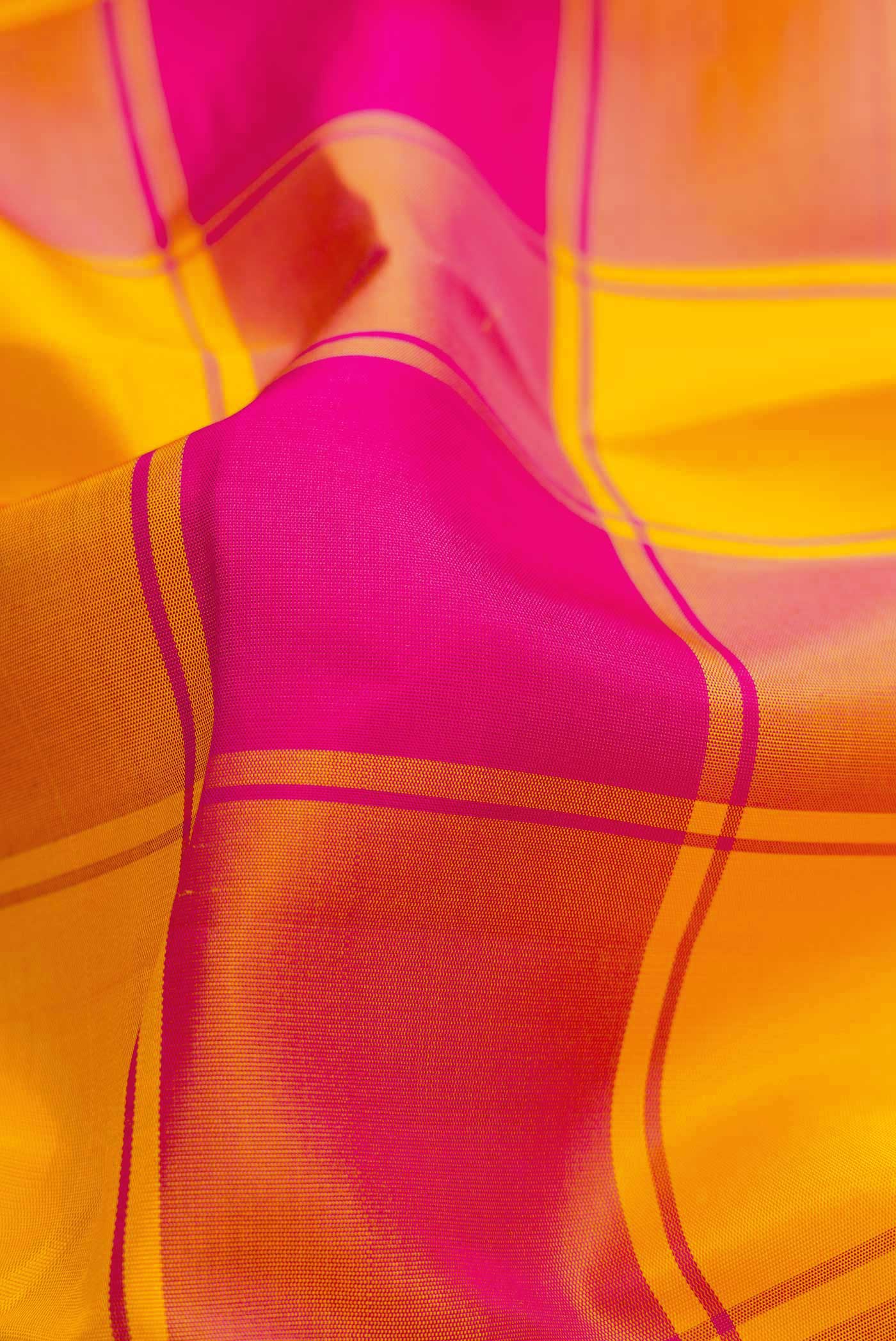 Close up of Pure Silk Pure Zari Yellow and Pink Color Kanchipuram Saree with Checked design on the body and Zari Border displaying folds