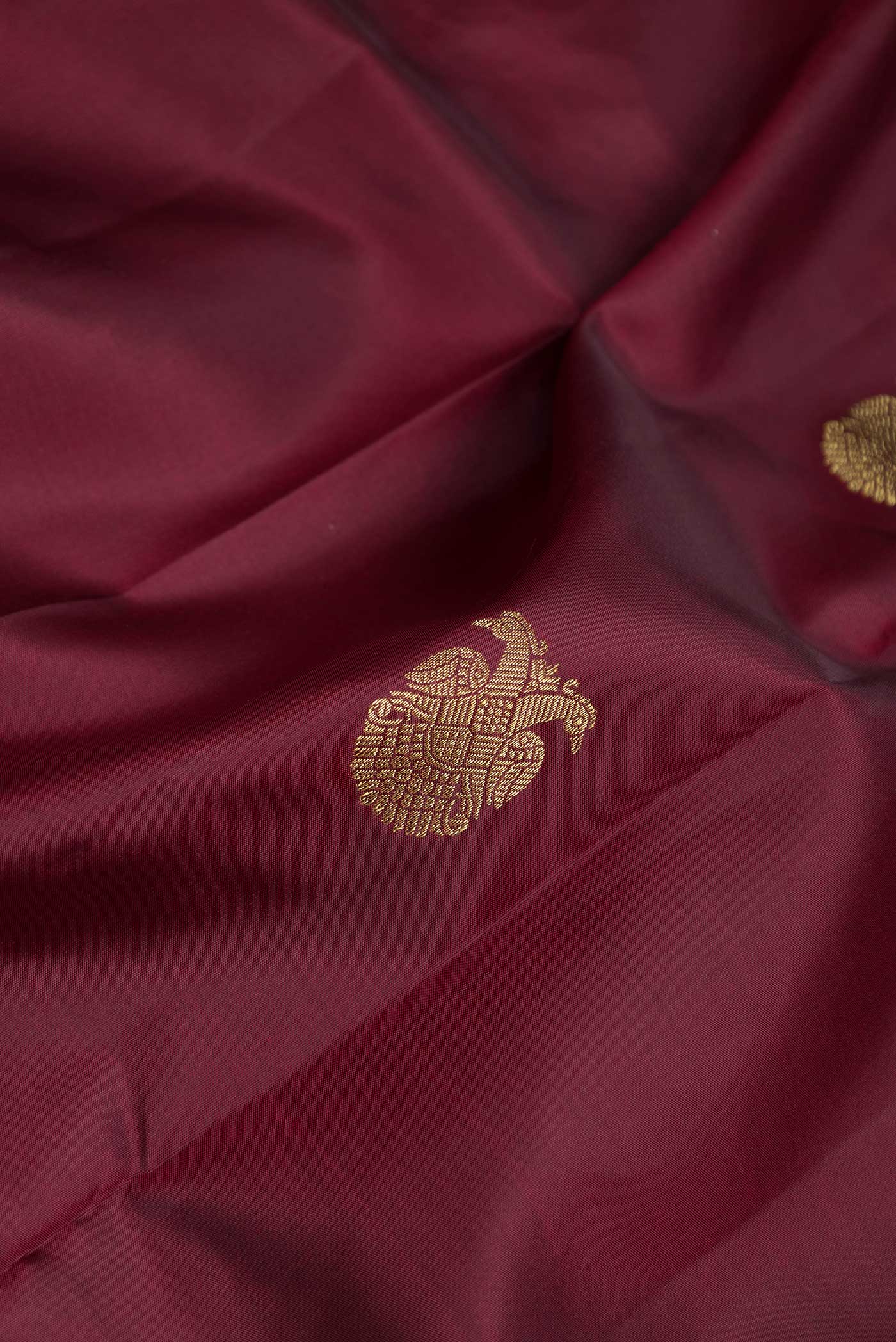 Close up of Maroon Dual Tone Kanchipuram Silk Saree with Zari Butta on the body and Zari Border displaying folds