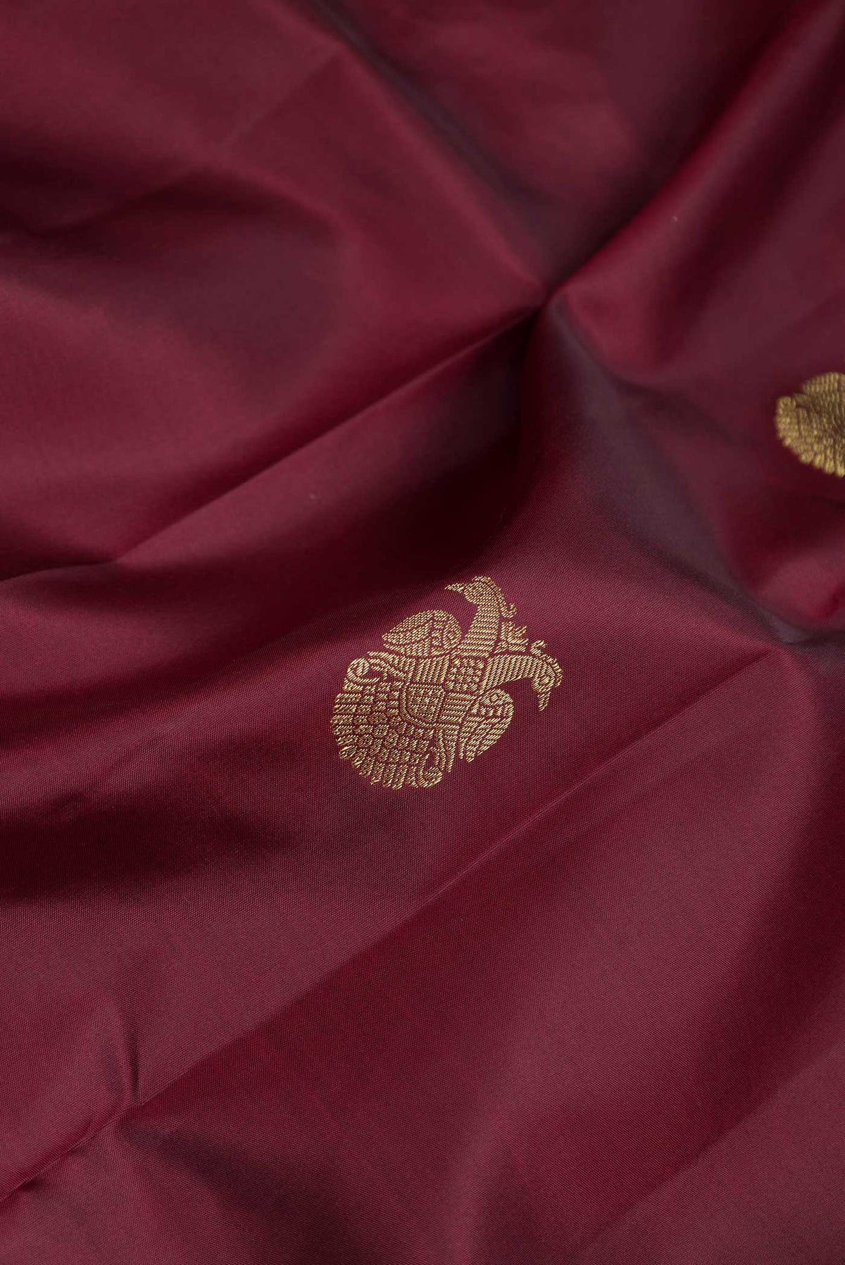 Close up of Maroon Dual Tone Kanchipuram Silk Saree with Zari Butta on the body and Zari Border displaying folds