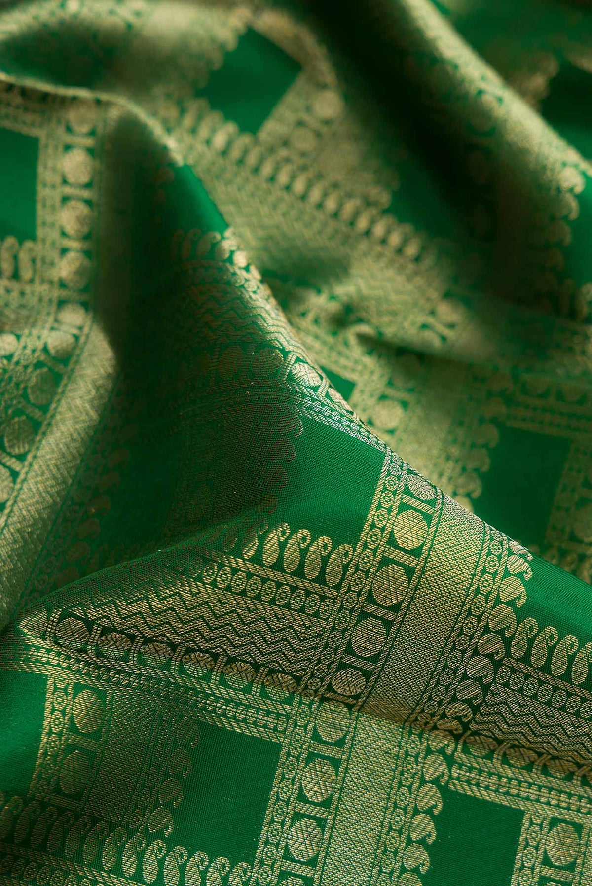 Close up of Green Dual Tone Kanjivaram Silk Saree with Zari Brocade on the body and Zari Border.  displaying folds