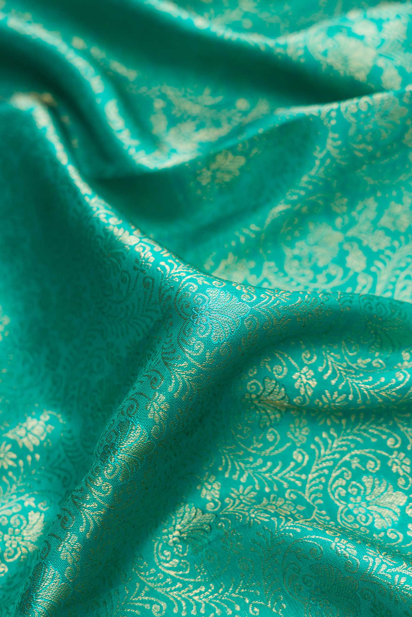 Close up of Green Dual Tone Kanjivaram Silk Saree with Zari Brocade on the body and Zari Border.  displaying folds