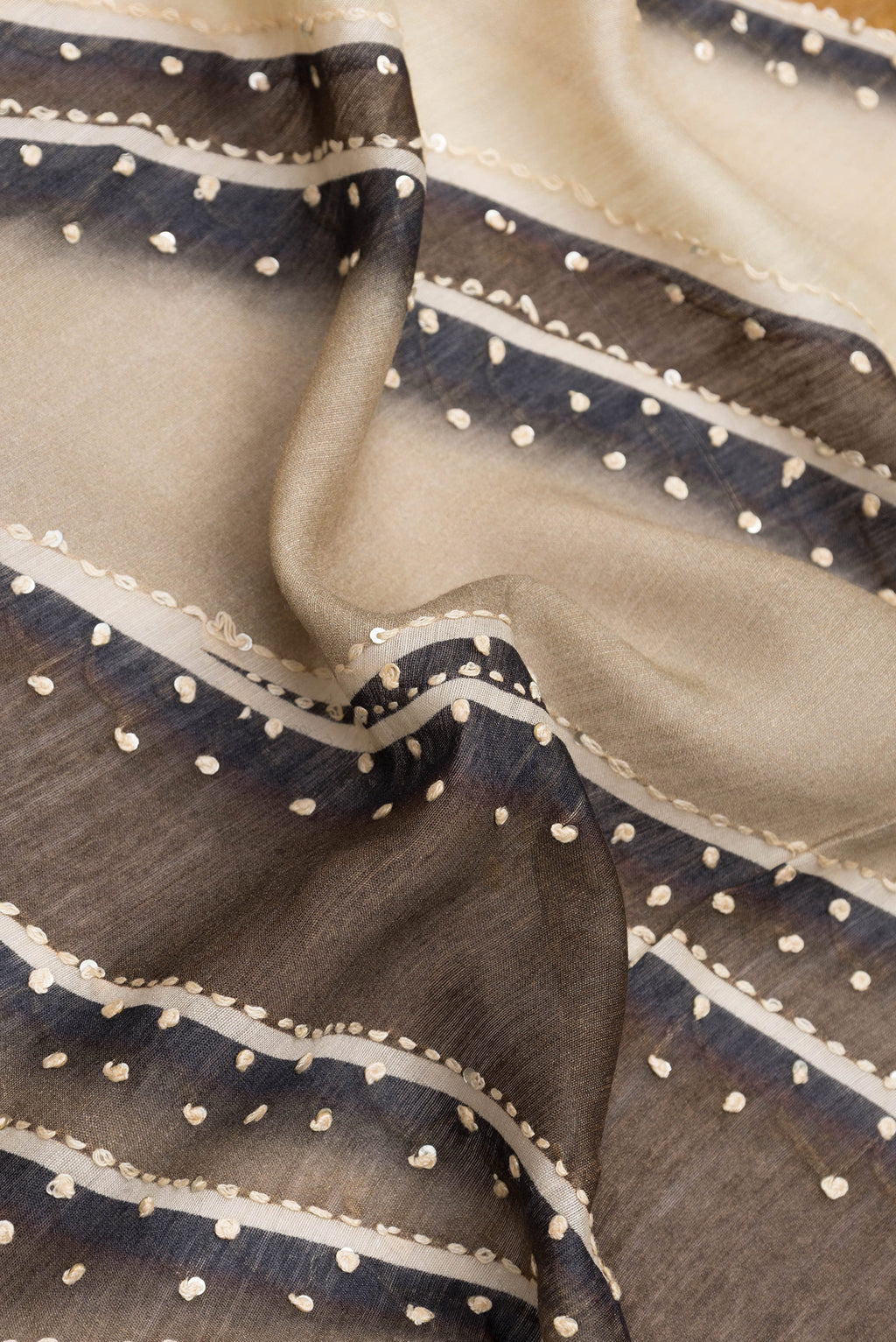Close up of Brown Dual Tone Tussar Silk Saree with Embroidery on the body and Zari Border.  displaying folds