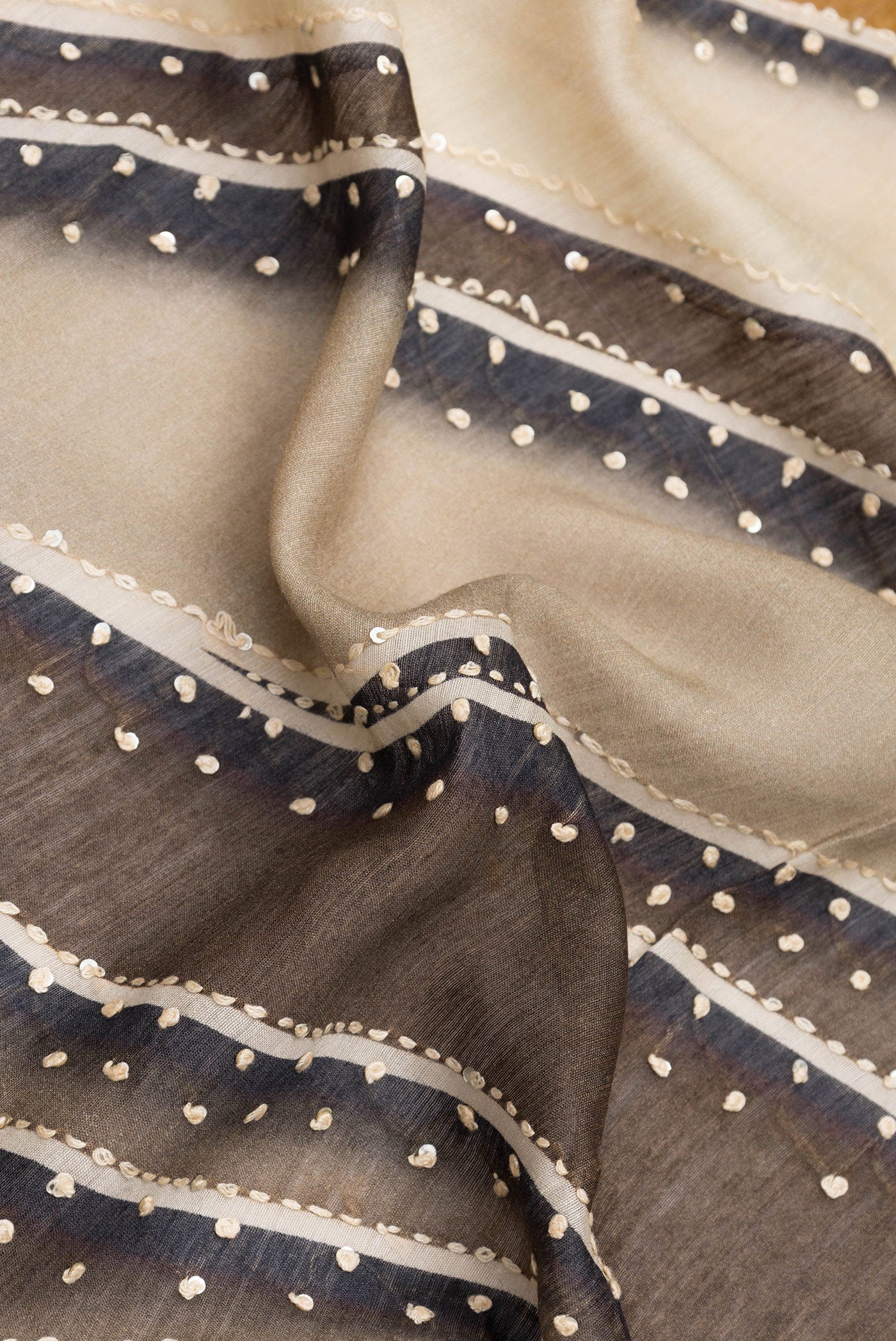 Close up of Brown Dual Tone Tussar Silk Saree with Embroidery on the body and Zari Border.  displaying folds