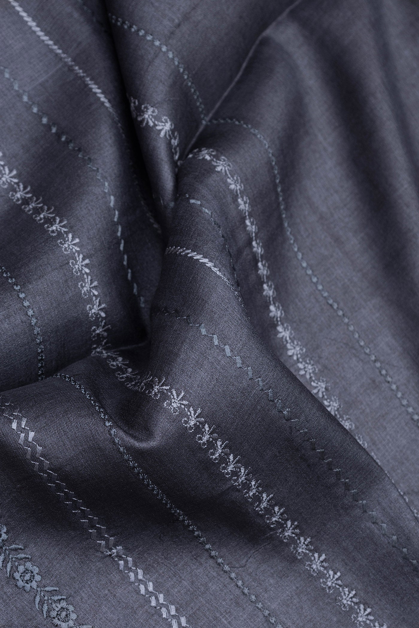 Close up of Grey Dual Tone Tussar Silk Saree with Embroidery on the body and Zari Border.  displaying folds