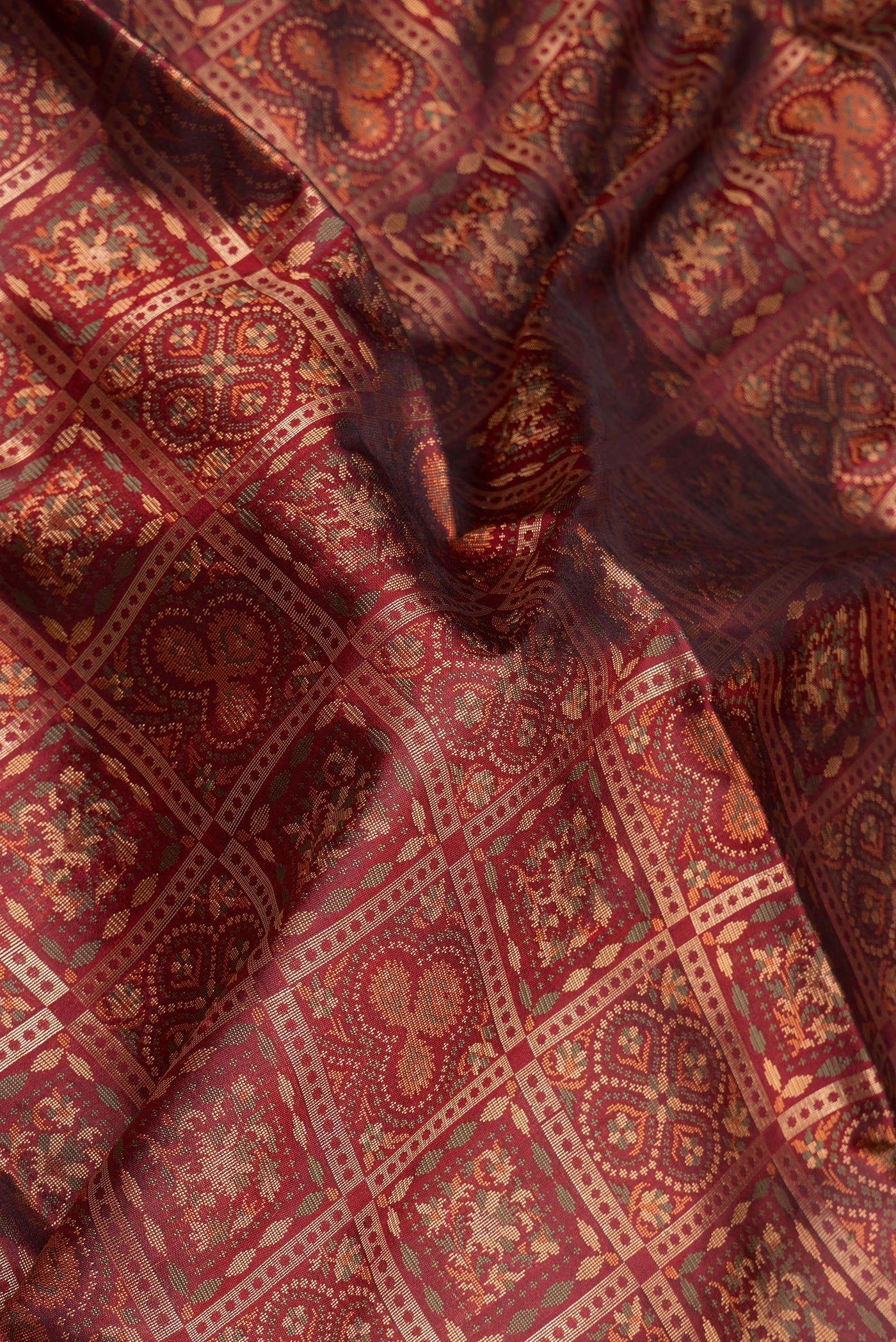 Close up of Maroon Banarasi Silk Saree with Checked design on the body and Zari And Thread Border.  displaying folds