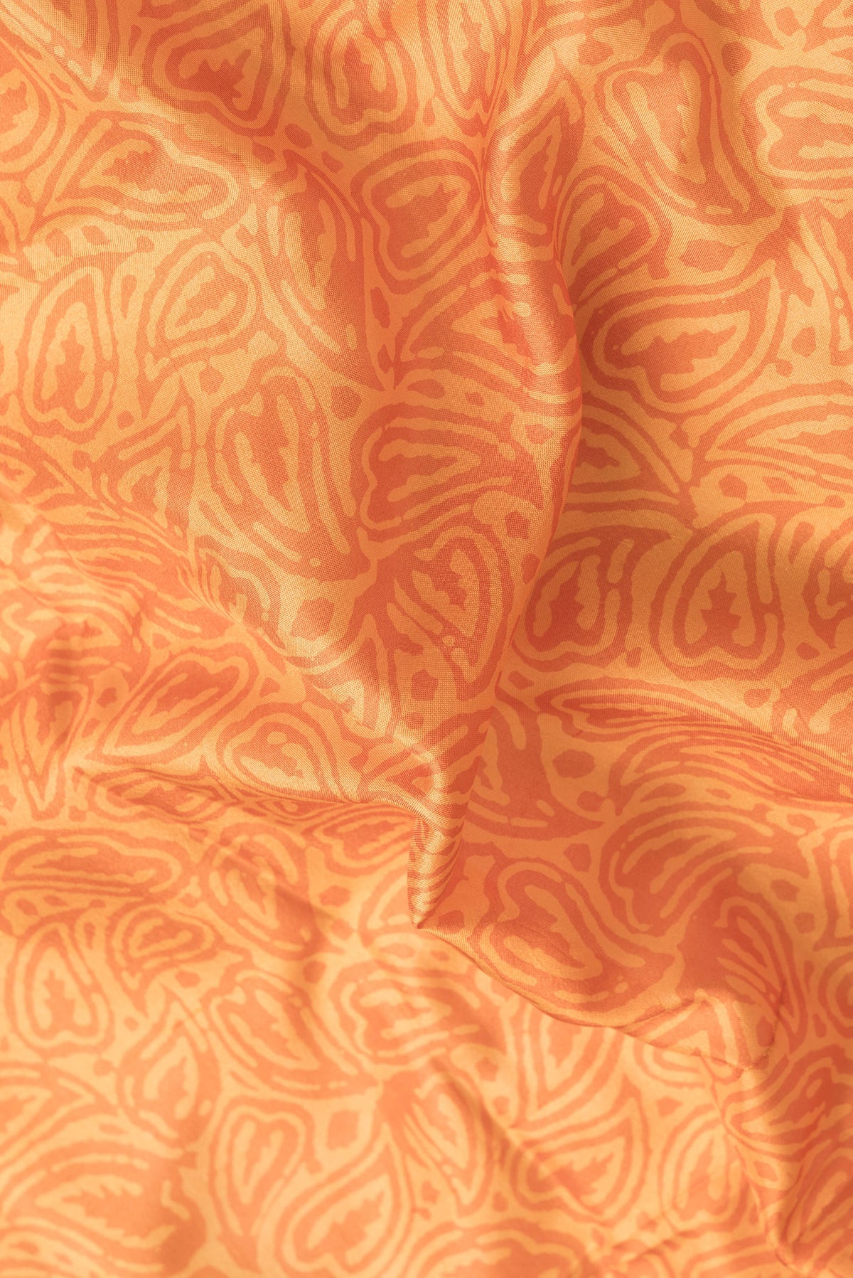 Close up of Orange Dual Tone Printed Silk Saree with Printed design on the body and Printed Border.  displaying folds