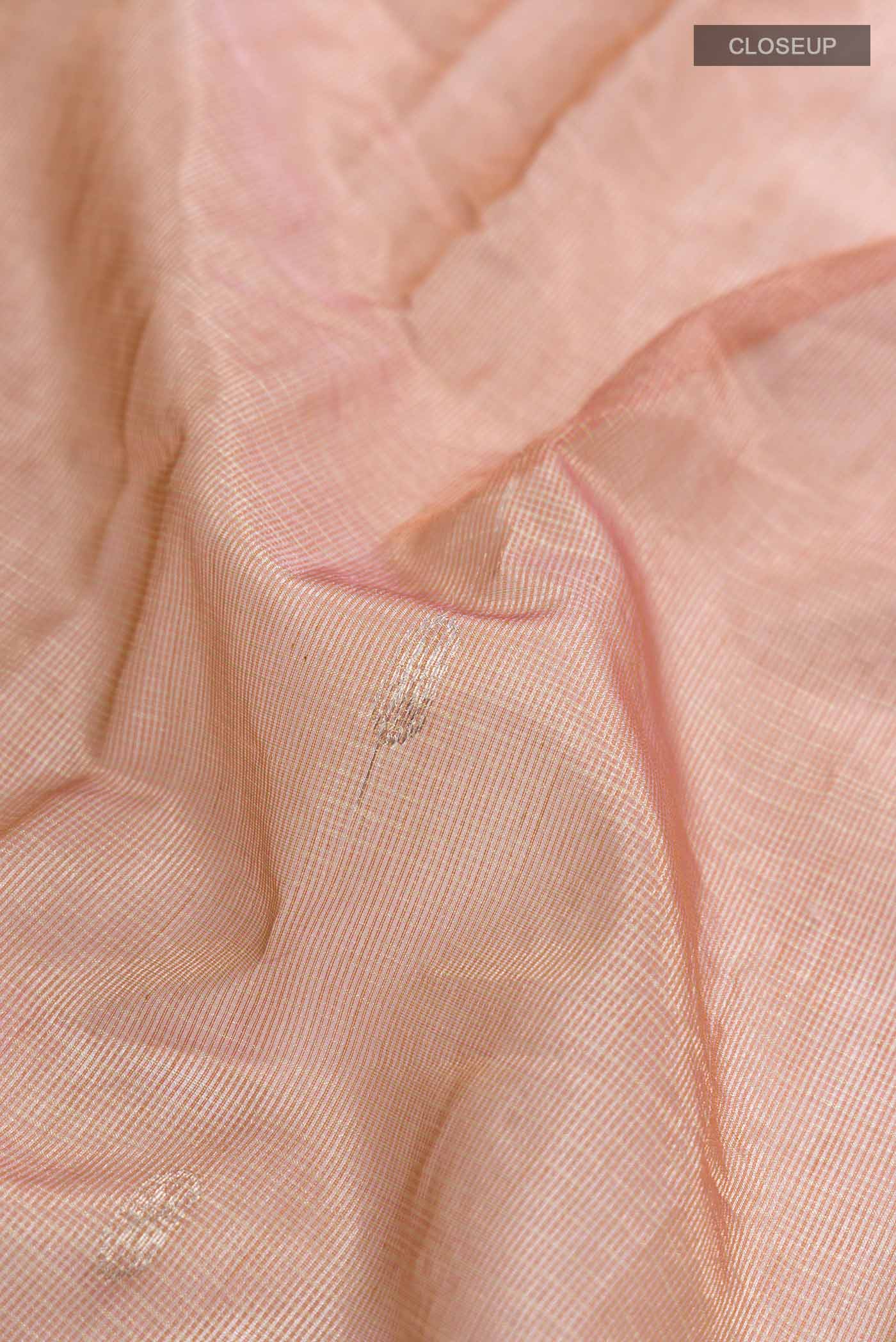 Close up of Peach Maheshwari Silk Cotton Saree with Zari Butta on the body and Zari Border displaying folds