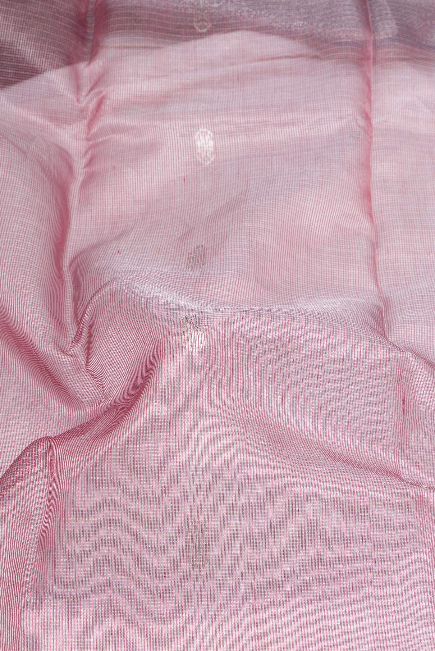 Close up of Rose Gold Maheshwari Tissue Silk Cotton Saree with Zari Butta on the body and Zari Border.  displaying folds