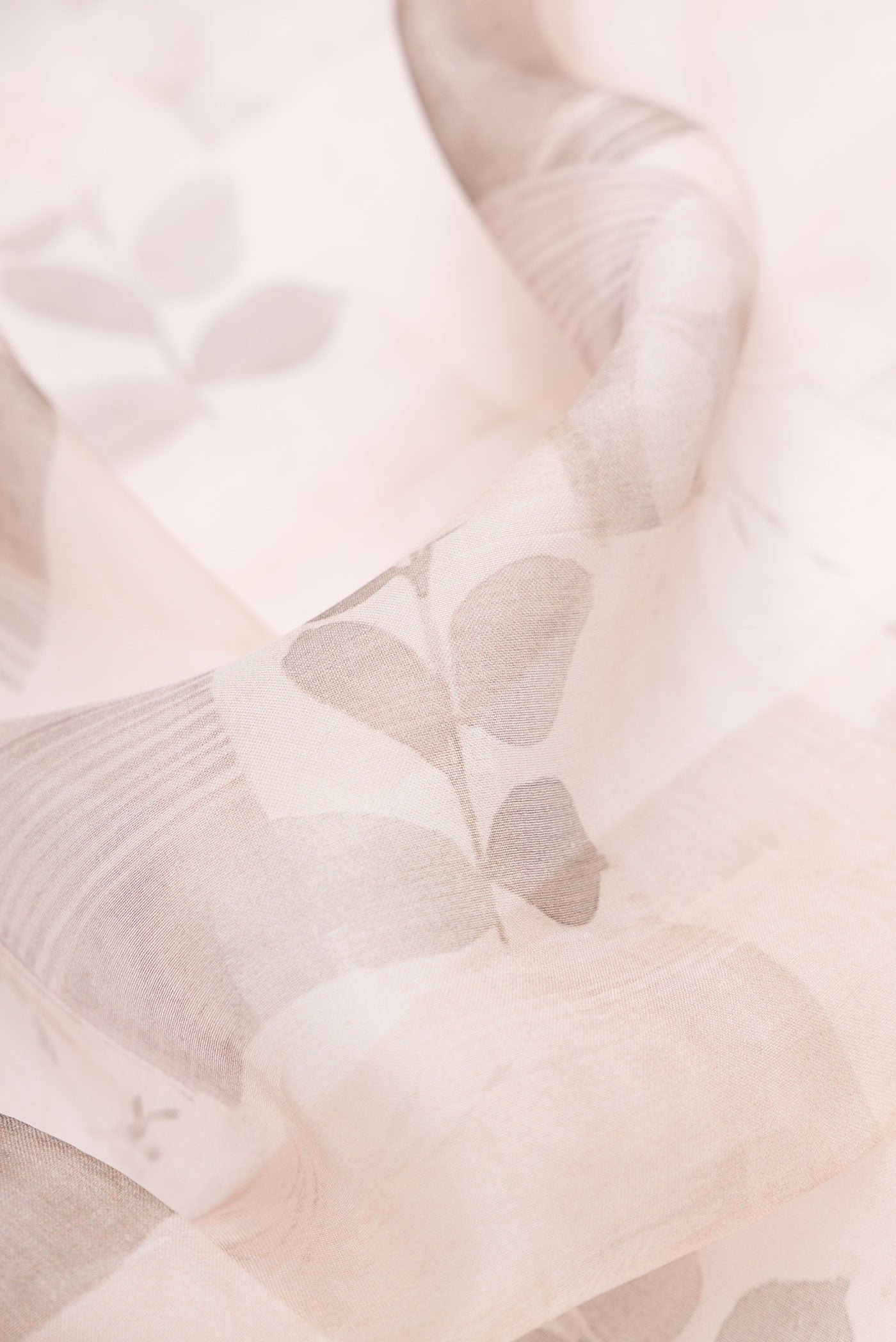 Close up of Rose Gold Dual Tone Organza Silk Saree with Printed design on the body and Printed Border.  displaying folds