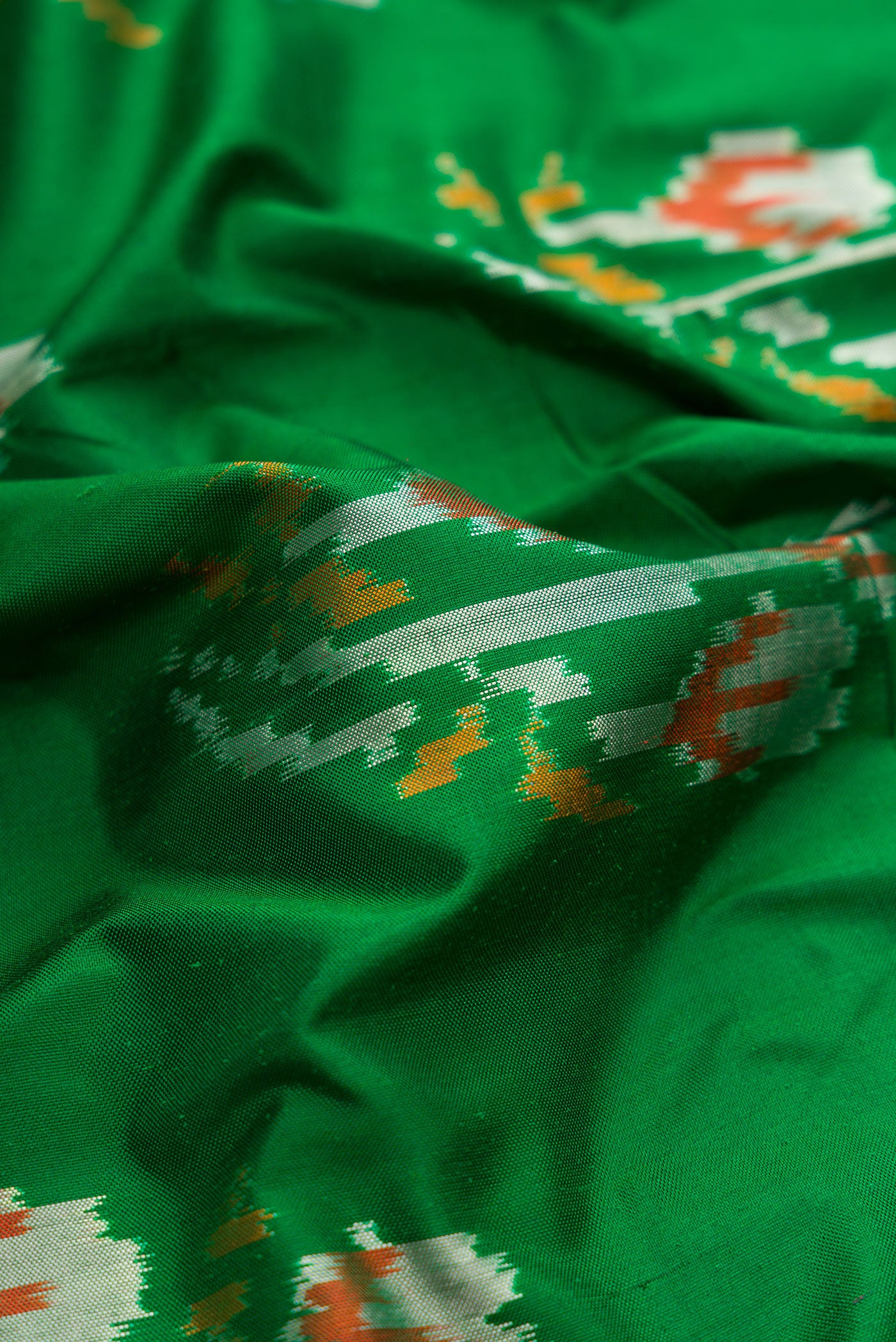 Close up of Green Dual Tone Double Ikat Saree with Ikat Print on the body and Ikat Border.  displaying folds