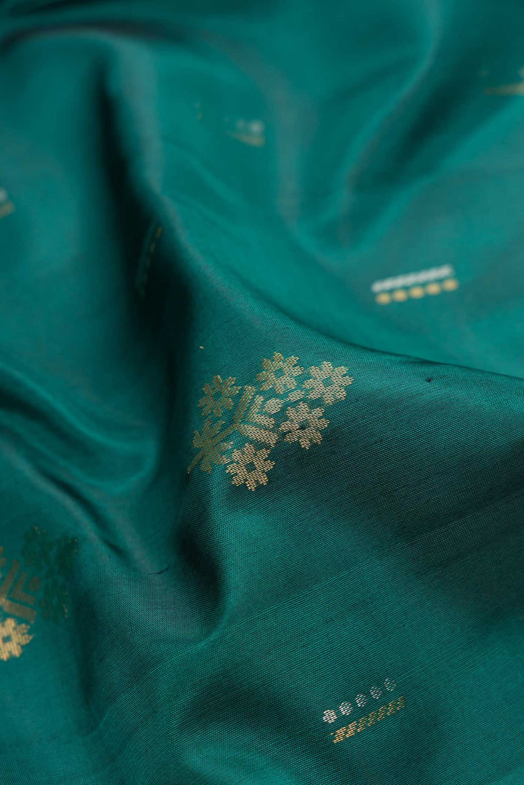 Close up of Green Dual Tone Soft Silk Saree with Zari Butta on the body and Zari Border.  displaying folds