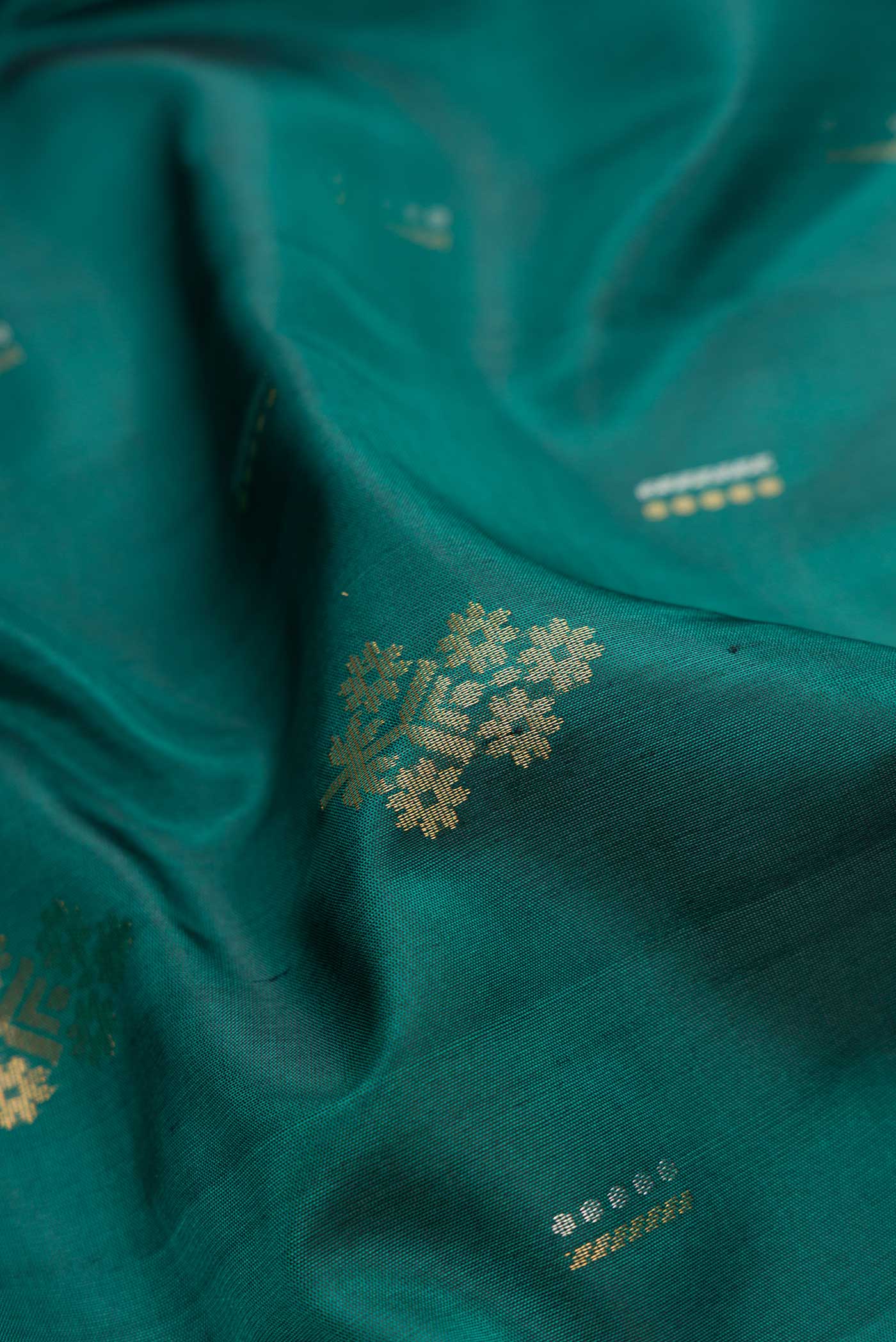 Close up of Green Dual Tone Soft Silk Saree with Zari Butta on the body and Zari Border.  displaying folds