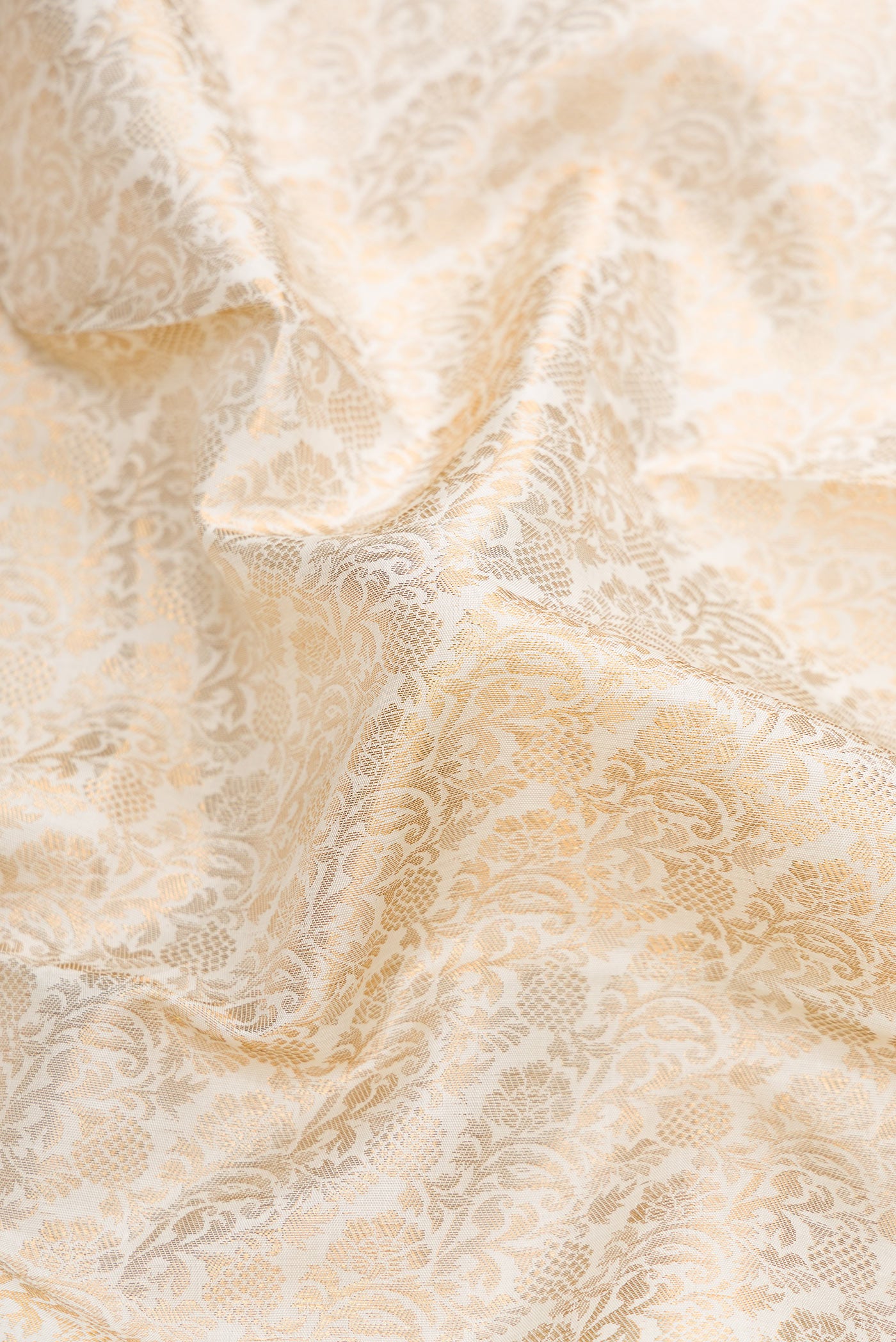 Close up of Off White Dual Tone Kanchipuram Silk Saree with Zari Brocade on the body and Zari Border.  displaying folds