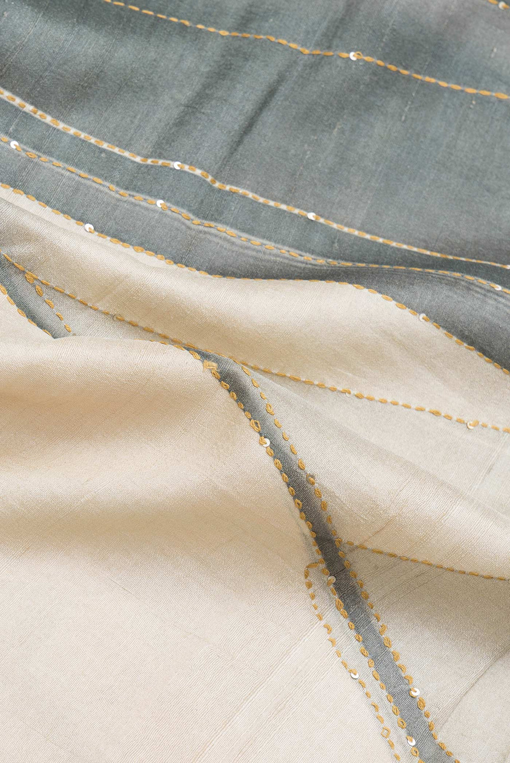 Close up of Beige Dual Tone Tussar Silk Saree with Printed design on the body and Zari Border.  displaying folds