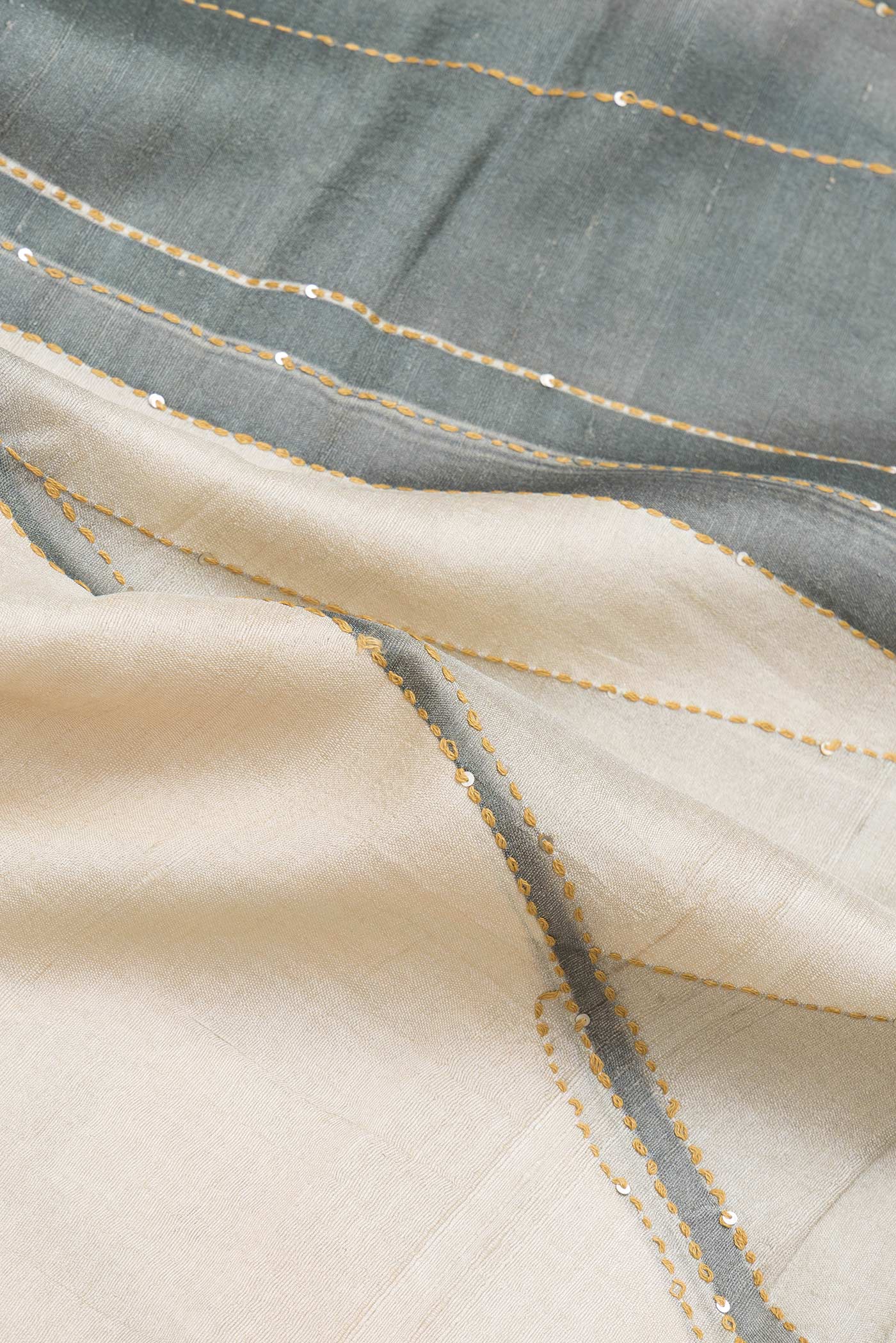 Close up of Beige Dual Tone Tussar Silk Saree with Printed design on the body and Zari Border.  displaying folds