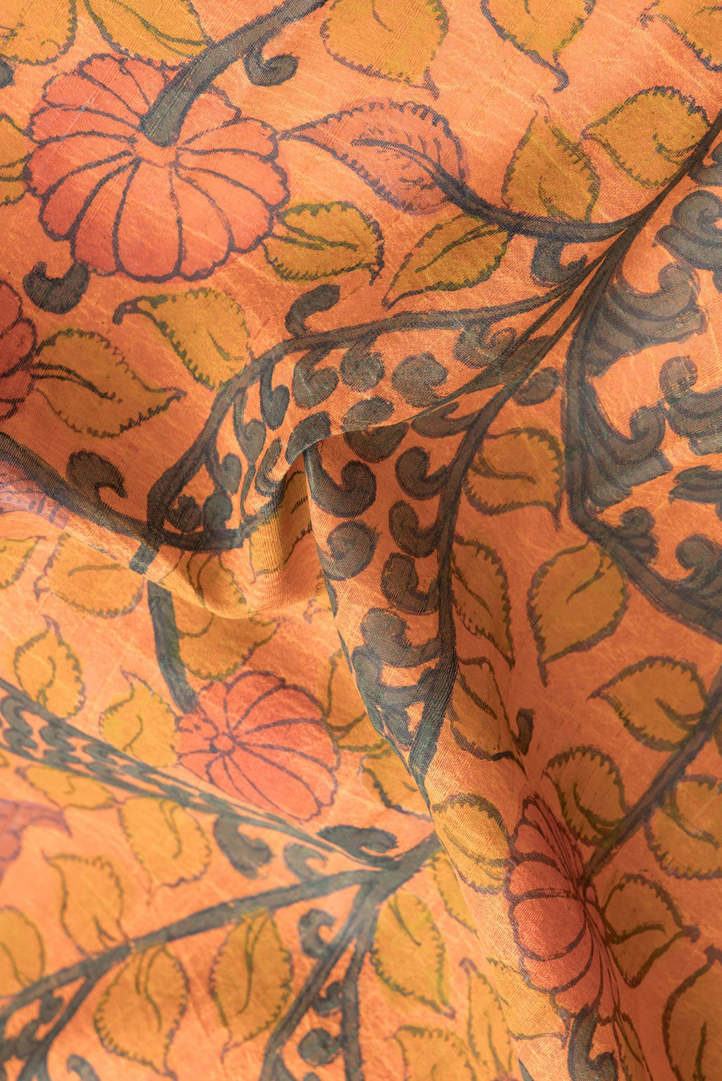 Close up of Orange Dual Tone Tussar Silk Saree with kalamkari Print on the body and Printed Border.  displaying folds