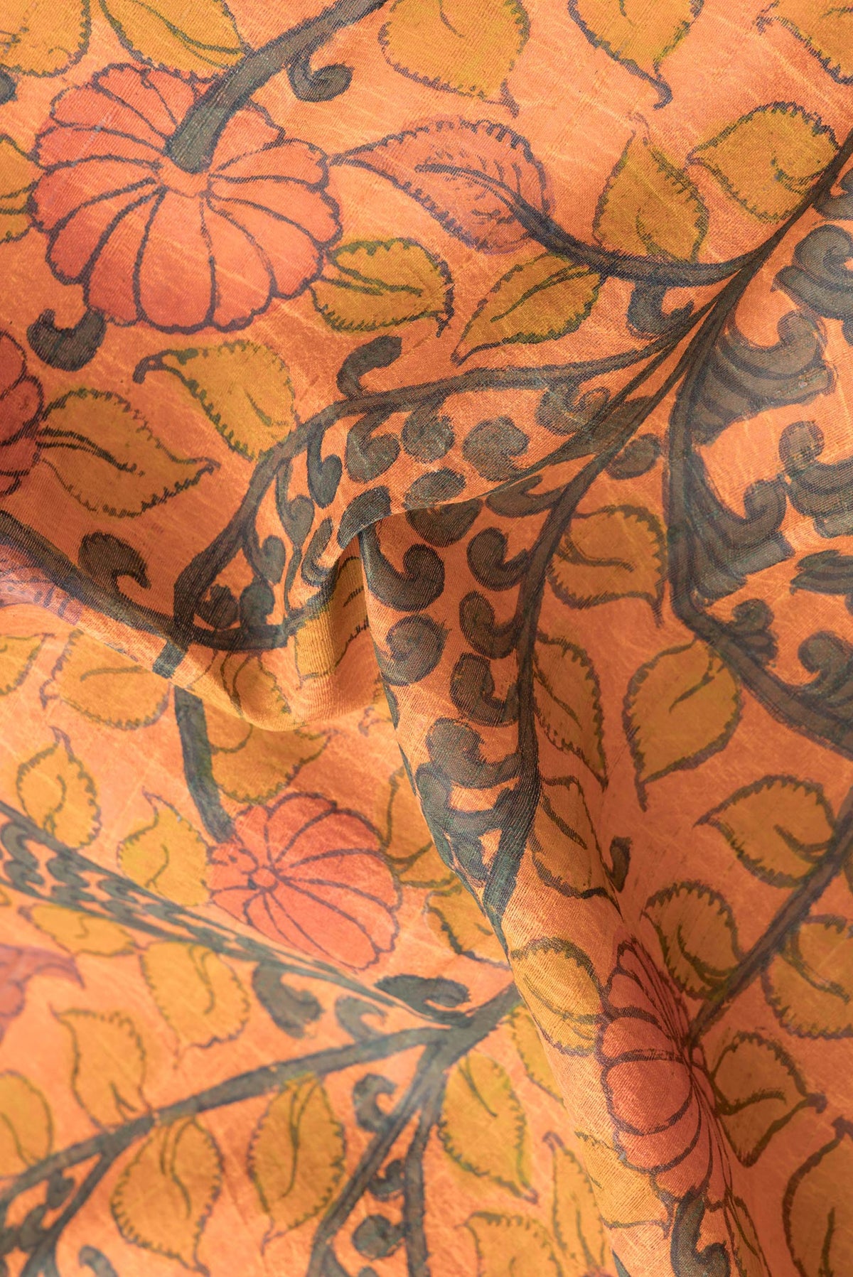 Close up of Orange Dual Tone Tussar Silk Saree with kalamkari Print on the body and Printed Border.  displaying folds