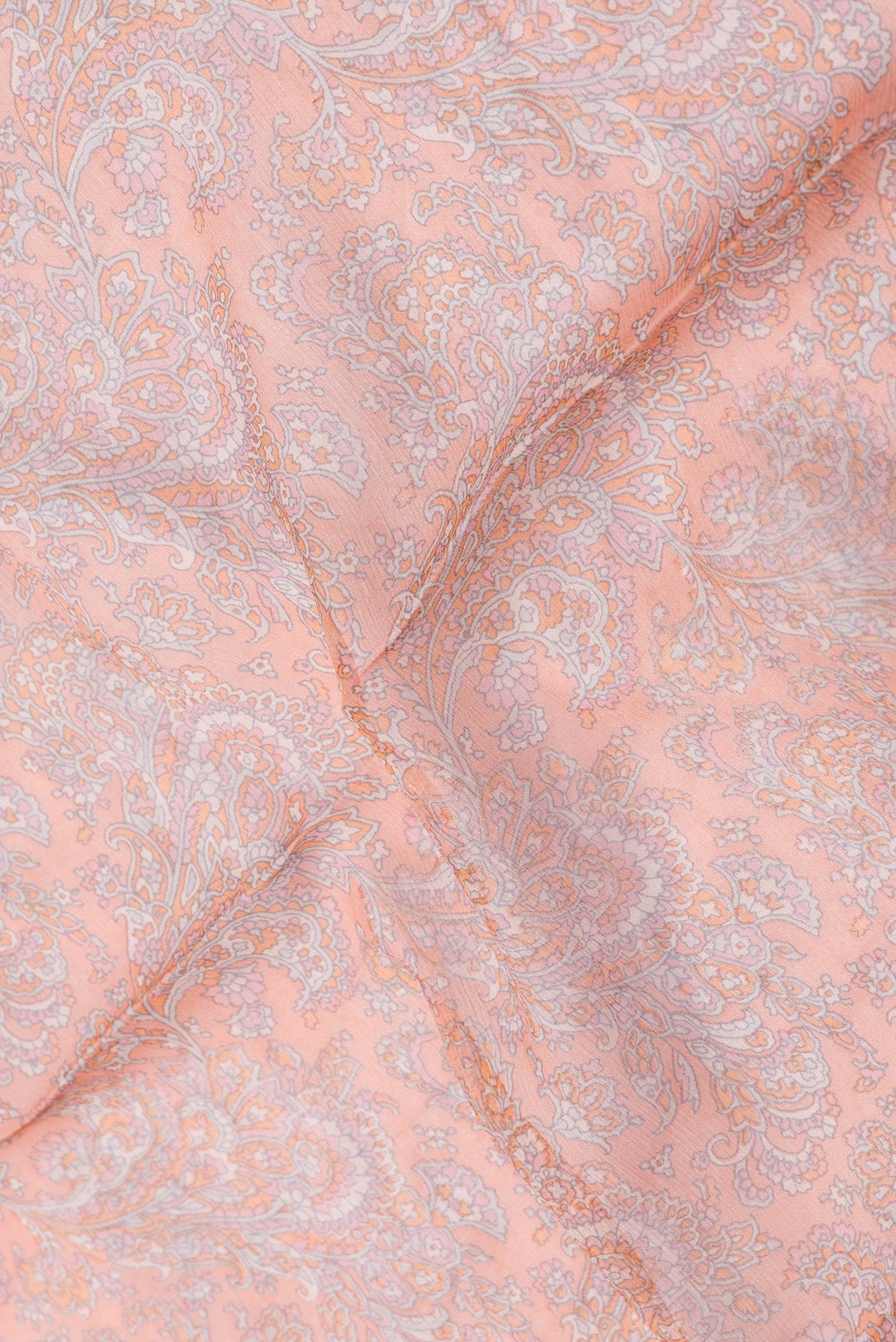 Close up of Peach Dual Tone Mysore Chiffon Saree with Printed design on the body and Thread Border.  displaying folds