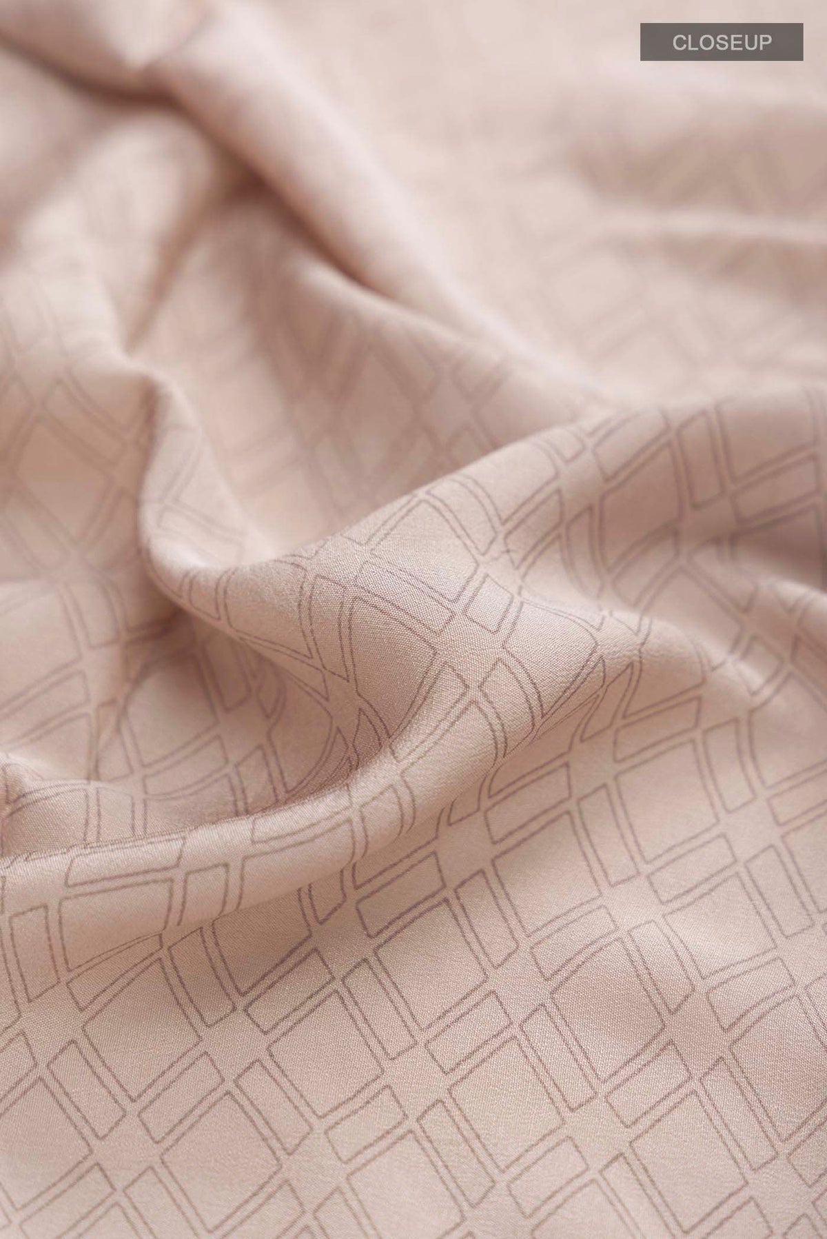 Close up of Grey Crepe Saree with Printed design on the body and Embroidery Border displaying folds