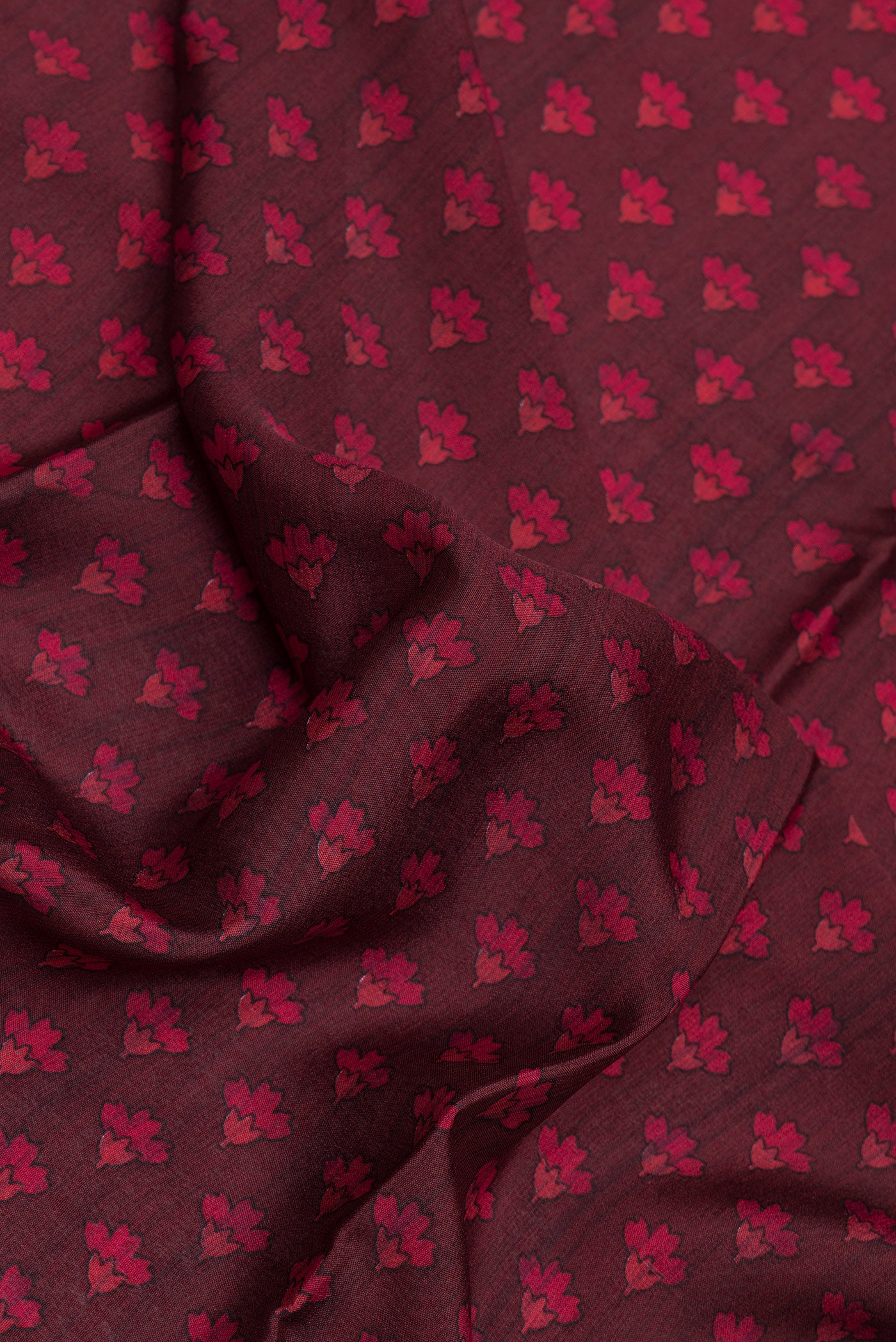 Close up of Maroon Dual Tone Crepe Saree with Printed design on the body and Zari Border.  displaying folds