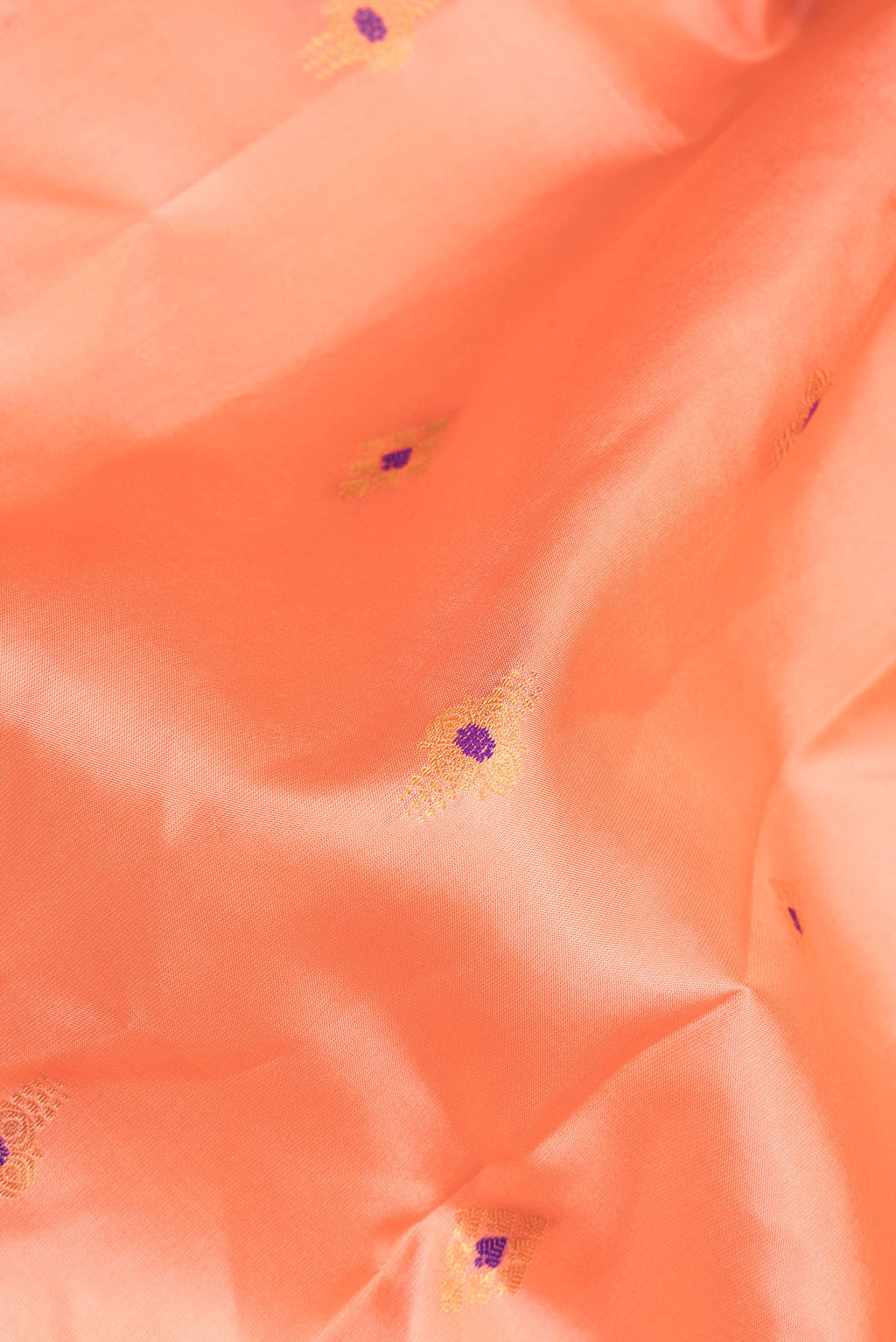 Close up of Pure Silk Peach Dual Tone Soft Saree with Zari And Thread Butta on the body and Fancy Border.  displaying folds