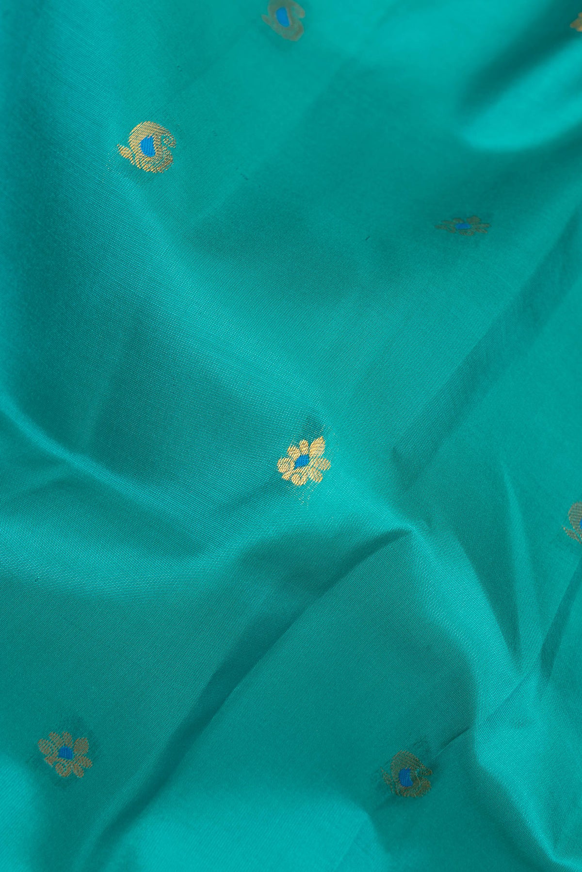 Close up of Pure Silk Peacock Blue Dual Tone Soft Saree with Zari And Thread Butta on the body and Fancy Border.  displaying folds