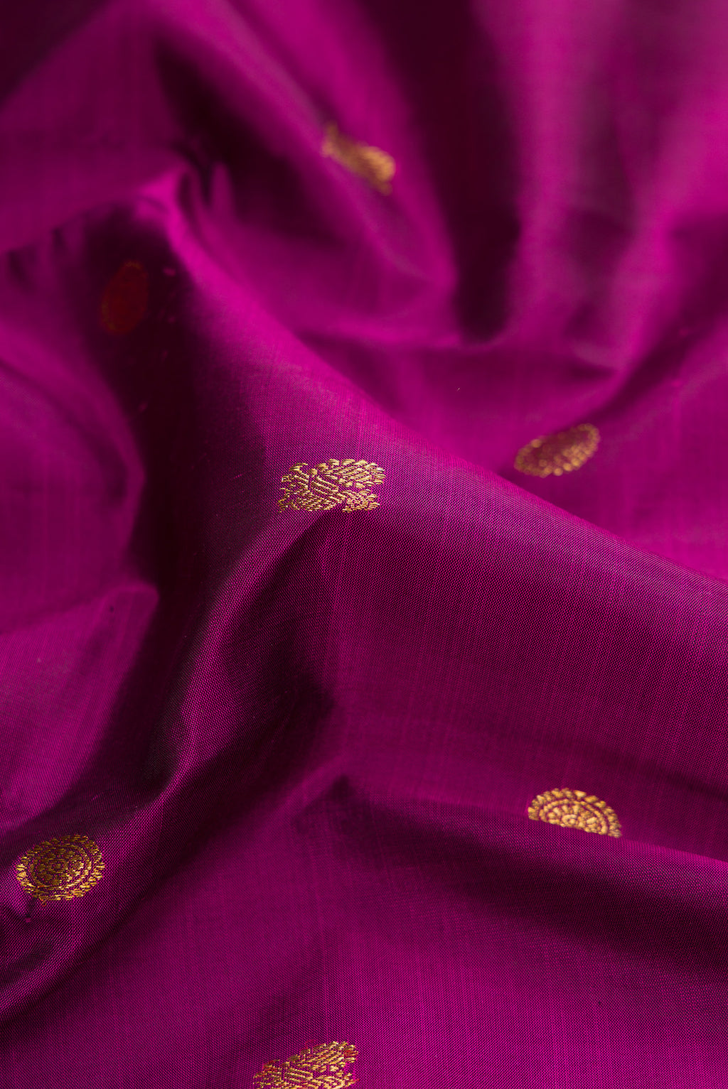 Close up of Pure Silk Pure Zari Magenta Dual Tone Kanjivaram Saree with Zari Butta on the body and Zari Border.  displaying folds