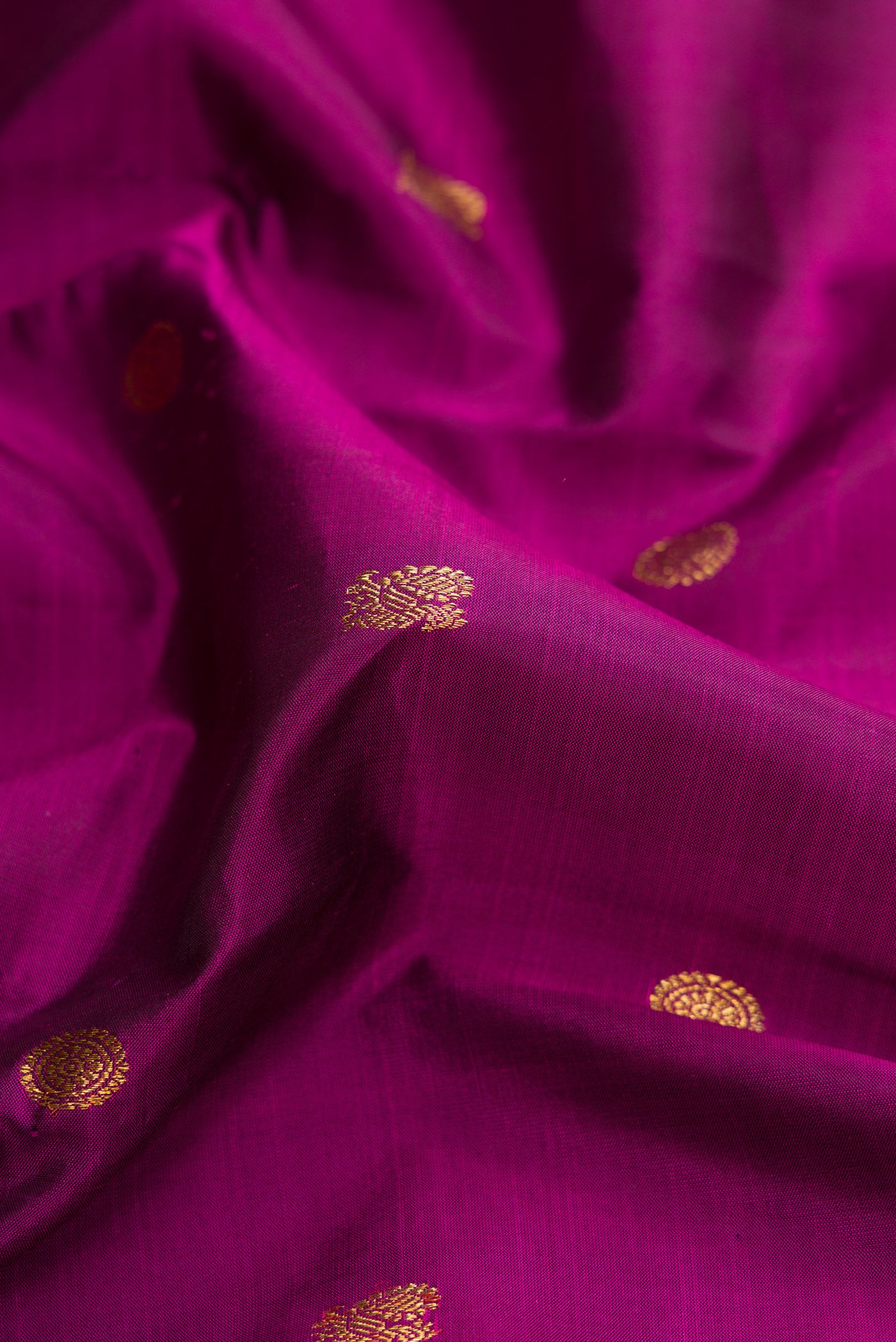 Close up of Pure Silk Pure Zari Magenta Dual Tone Kanjivaram Saree with Zari Butta on the body and Zari Border.  displaying folds