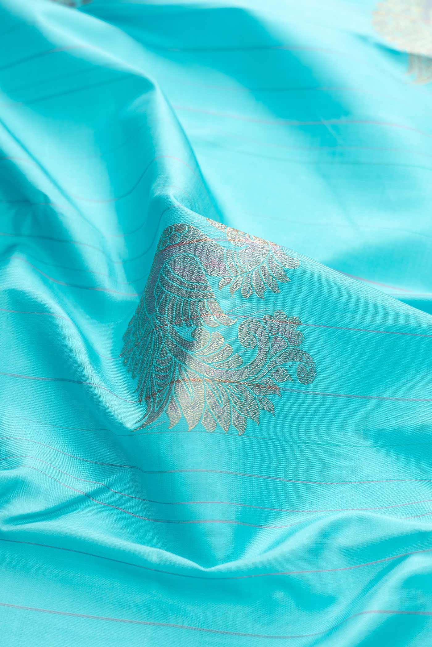 Close up of Sky Blue Dual Tone Kanchipuram Silk Saree with Zari Butta on the body and Without Border displaying folds