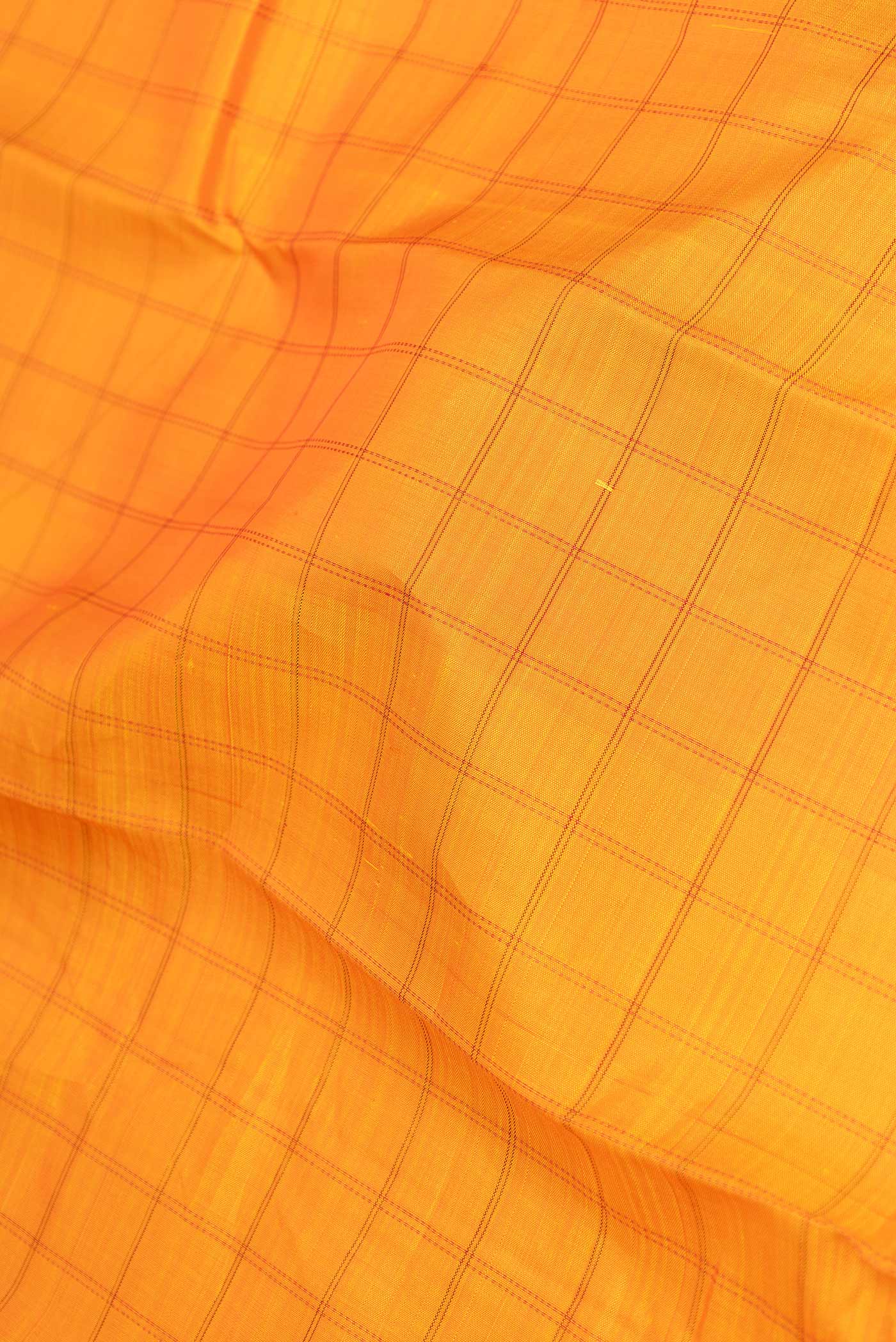 Close up of Orange Dual Tone Kanchipuram Saree with Checked design on the body and Without Border displaying folds