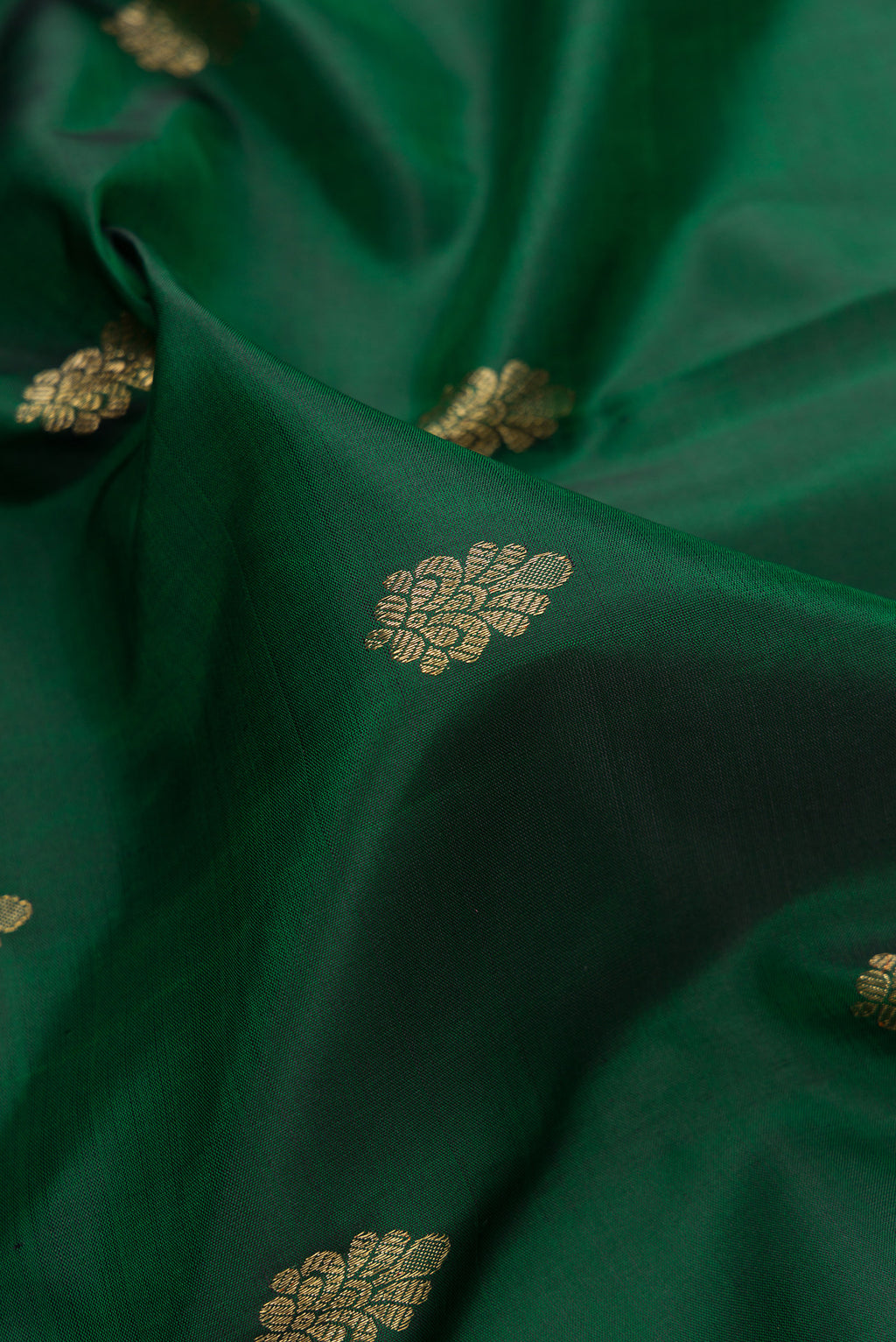 Close up of Pure Silk Pure Zari Bottle Green Dual Tone Kanchipuram Saree with Zari Butta on the body and Zari And Thread Border.  displaying folds