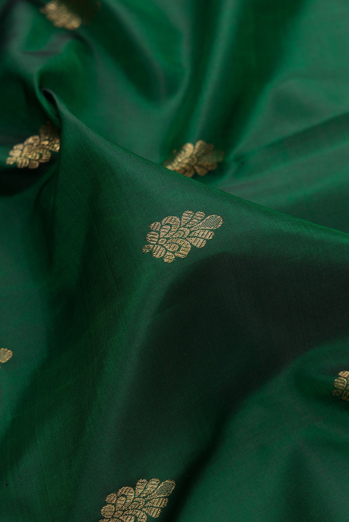 Close up of Pure Silk Pure Zari Bottle Green Dual Tone Kanchipuram Saree with Zari Butta on the body and Zari And Thread Border.  displaying folds