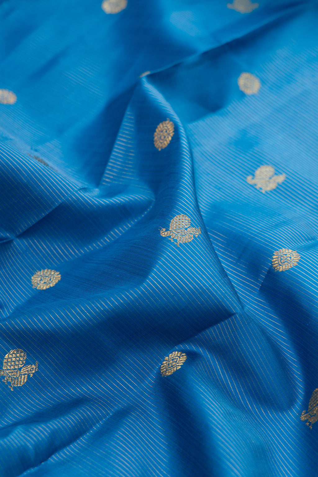 Close up of Pure Silk Pure Zari Peacock Blue Kanjivaram Saree with Zari Butta on the body and Zari Border.  displaying folds