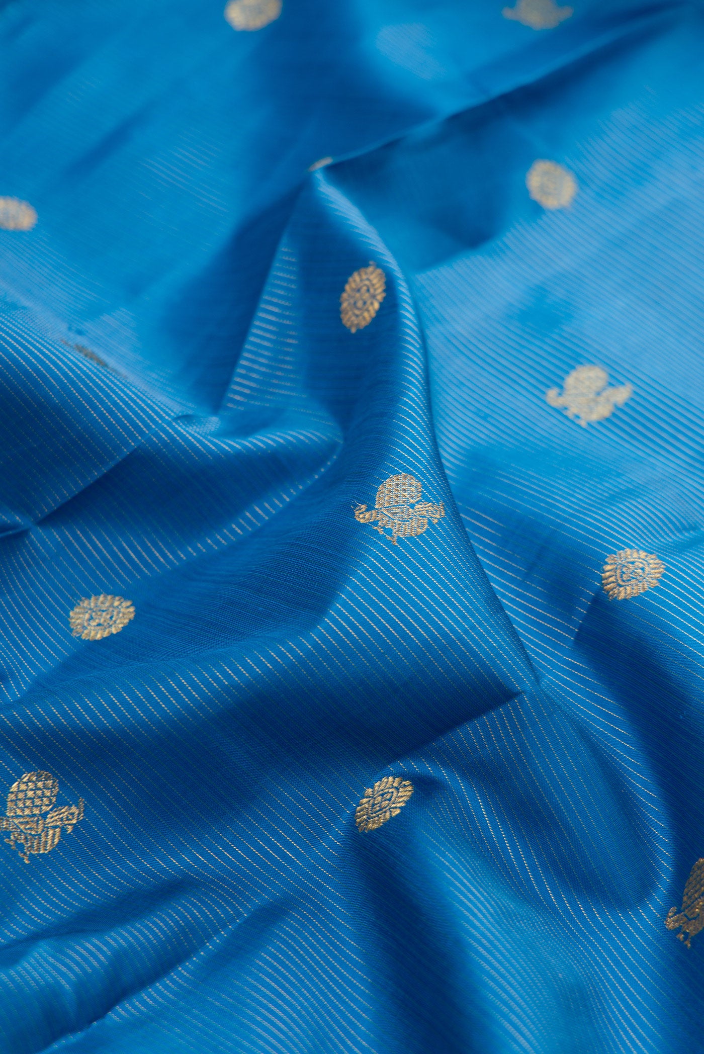 Close up of Pure Silk Pure Zari Peacock Blue Kanjivaram Saree with Zari Butta on the body and Zari Border.  displaying folds