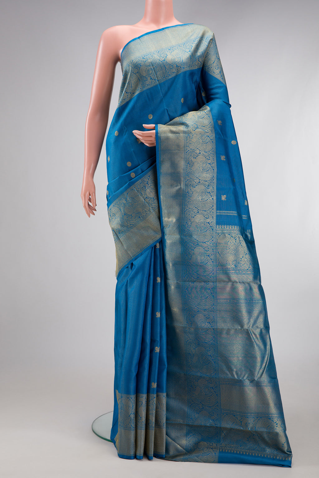 Pure Silk Pure Zari Peacock Blue Kanjivaram Saree with Zari Butta on the body and Zari Border.  displayed on a mannequin
