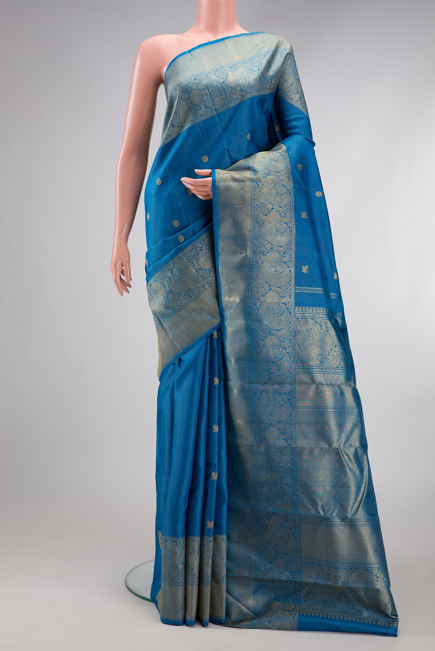 Pure Silk Pure Zari Peacock Blue Kanjivaram Saree with Zari Butta on the body and Zari Border.  displayed on a mannequin