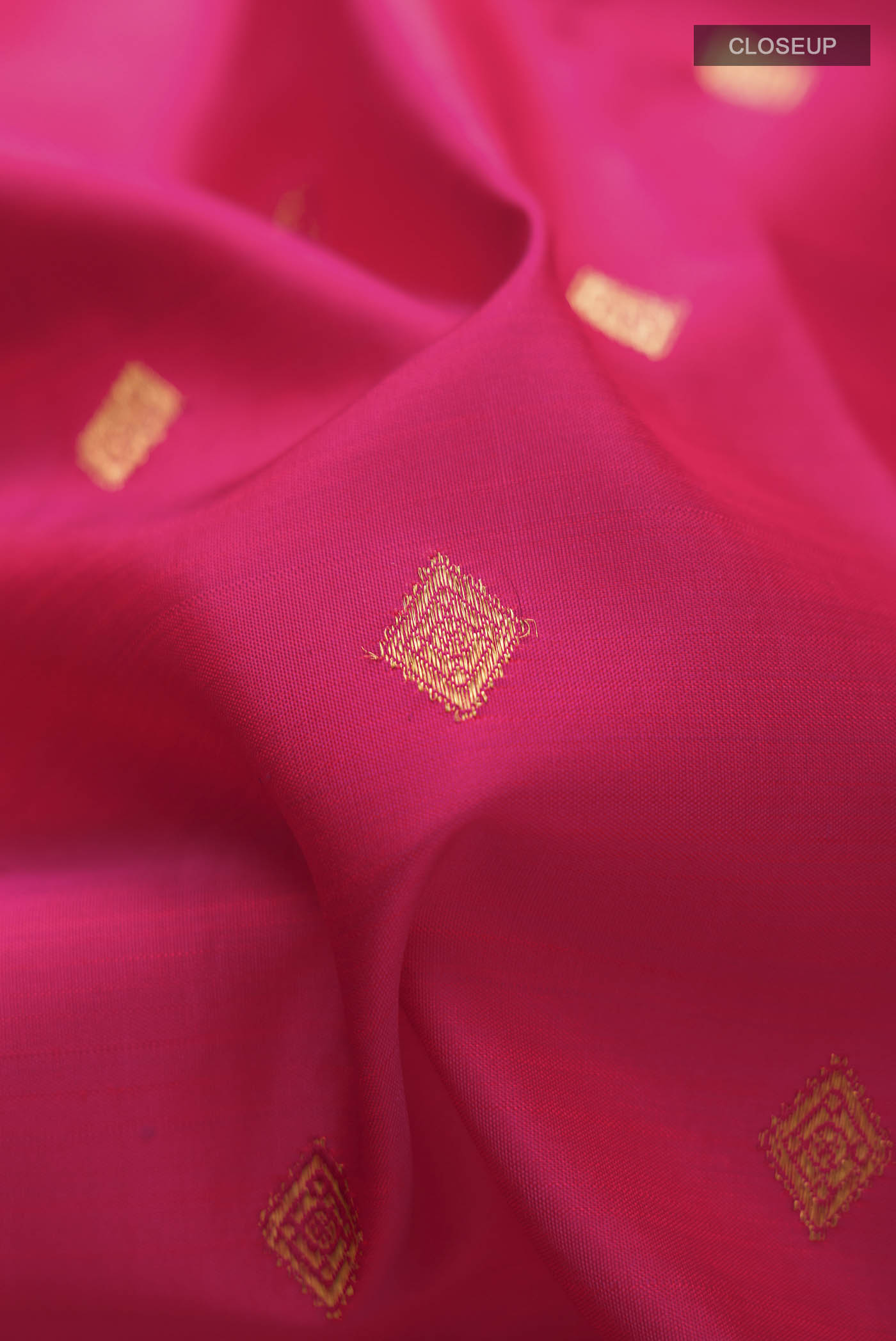Close up of Pink Kanchipuram Silk Saree with Zari Butta on the body and Zari Border displaying folds