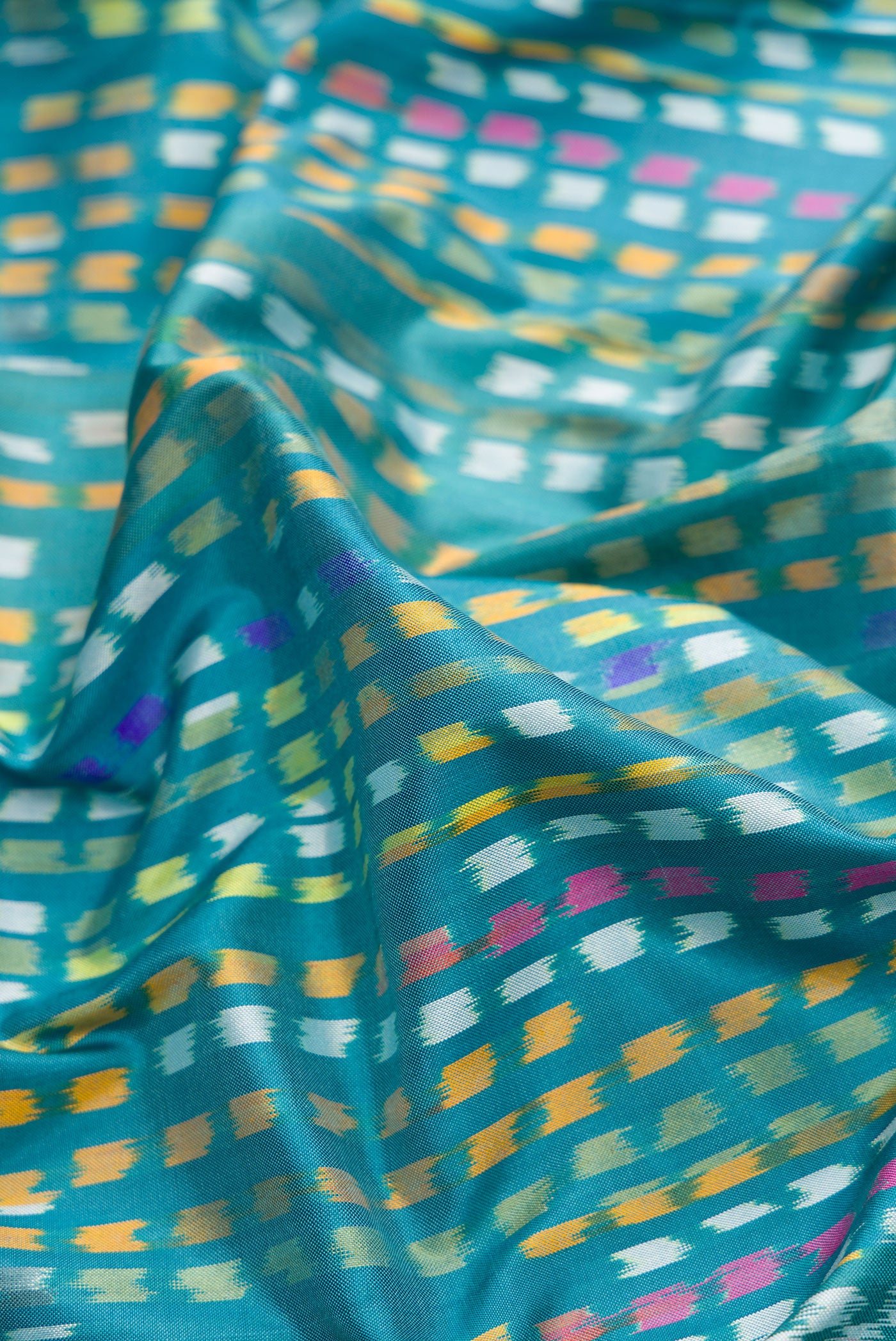 Close up of Peacock Blue Dual Tone Double Ikat Saree with Ikat Print on the body and Zari Border.  displaying folds