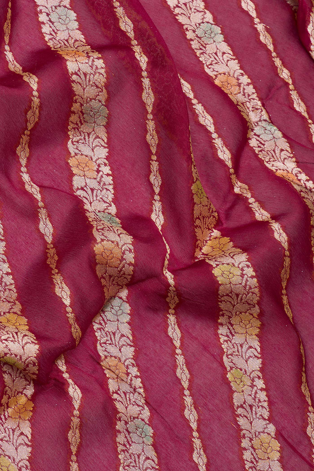 Close up of Maroon Banarasi Georgette Saree with Zari Brocade on the body and Zari And Thread Border.  displaying folds