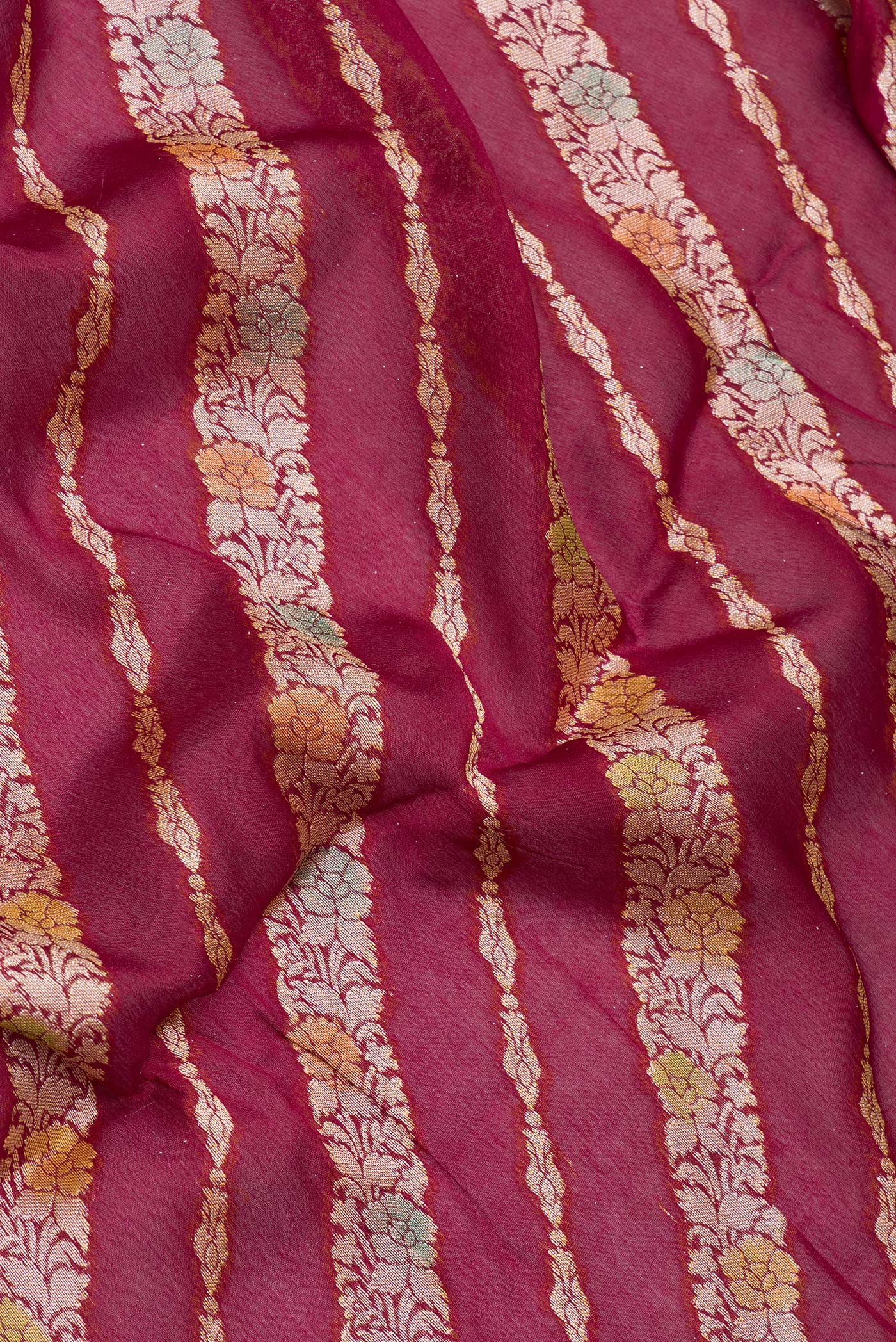 Close up of Maroon Banarasi Georgette Saree with Zari Brocade on the body and Zari And Thread Border.  displaying folds